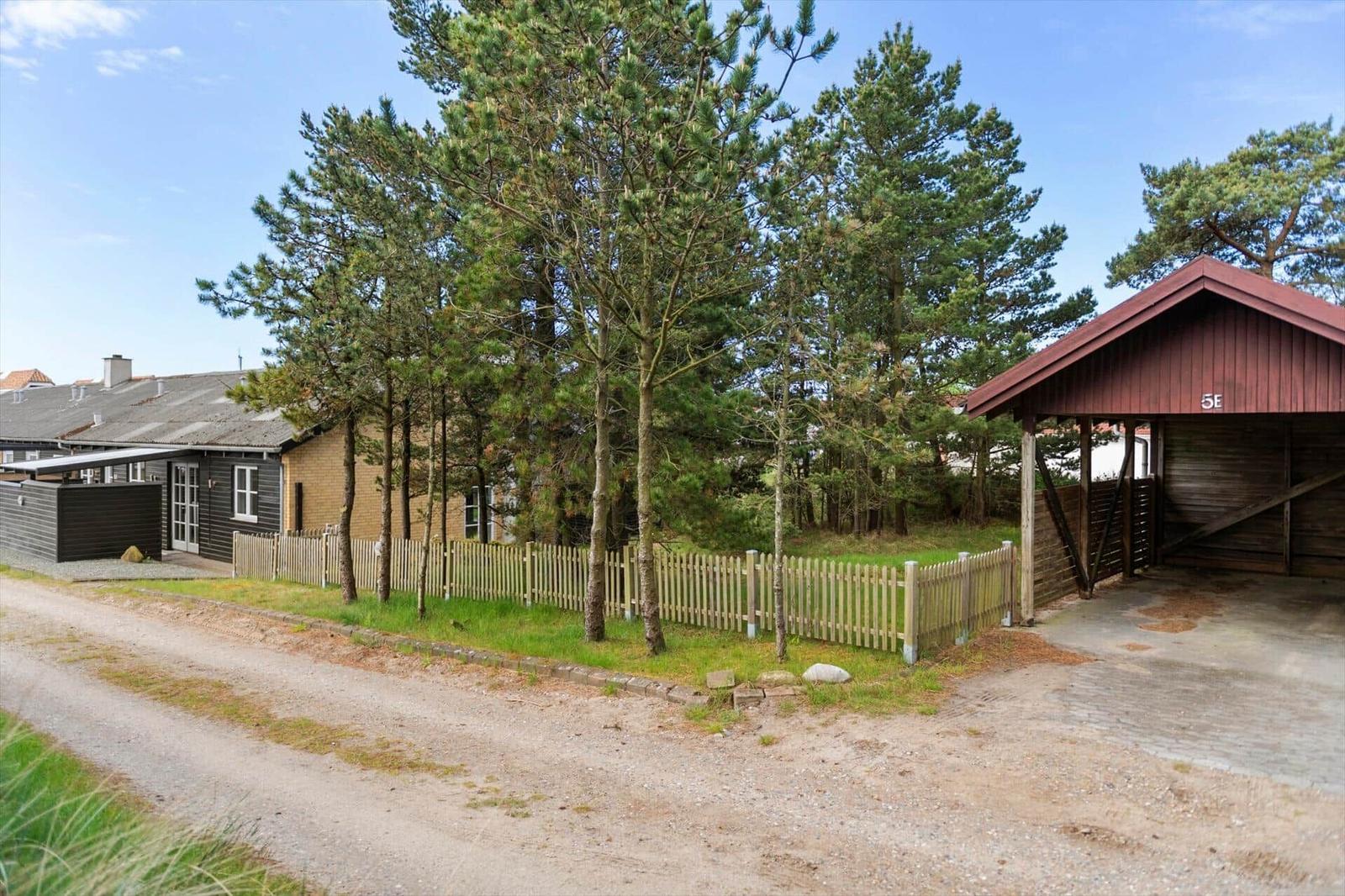 Haus mit Holzgarage und Zaun unter Bäumen