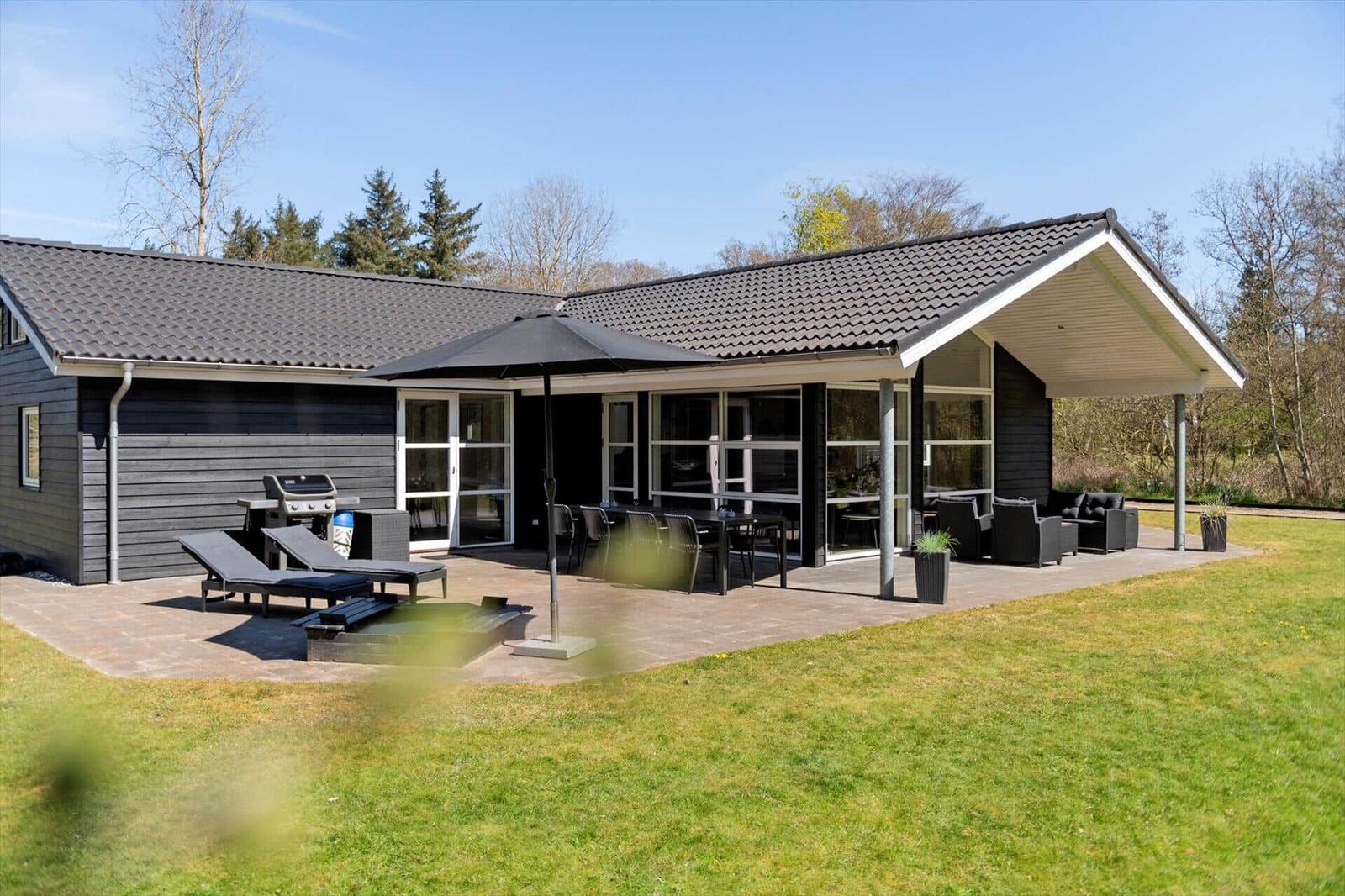 Modernes Haus mit großem Außenbereich, Grill und Sitzgelegenheiten.