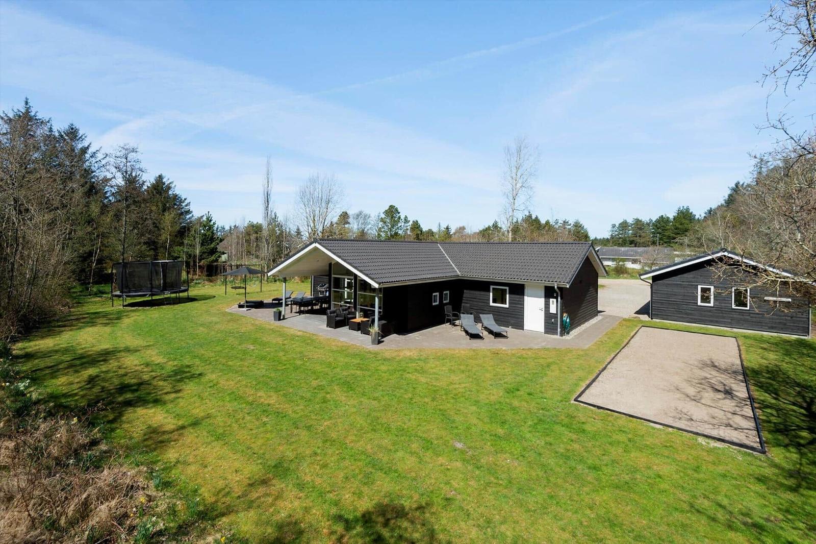 Moderne Holzhütte mit großem Garten, Terrasse und Trampolin. Nebengebäude und Sandkasten.
