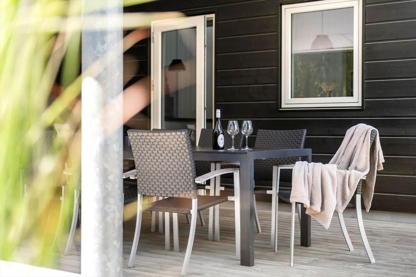Terrasse mit Tisch, Stühlen und einer Flasche Wein.