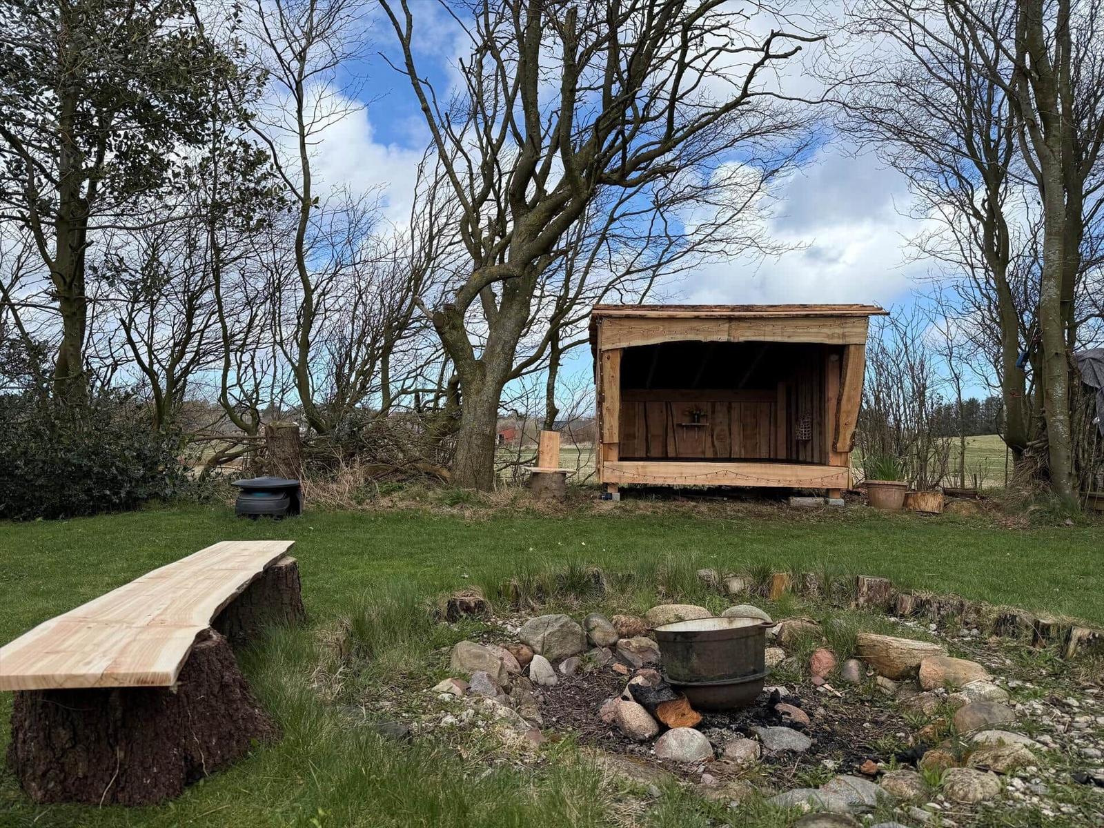 Wooden structure with grill area and bench outdoors.