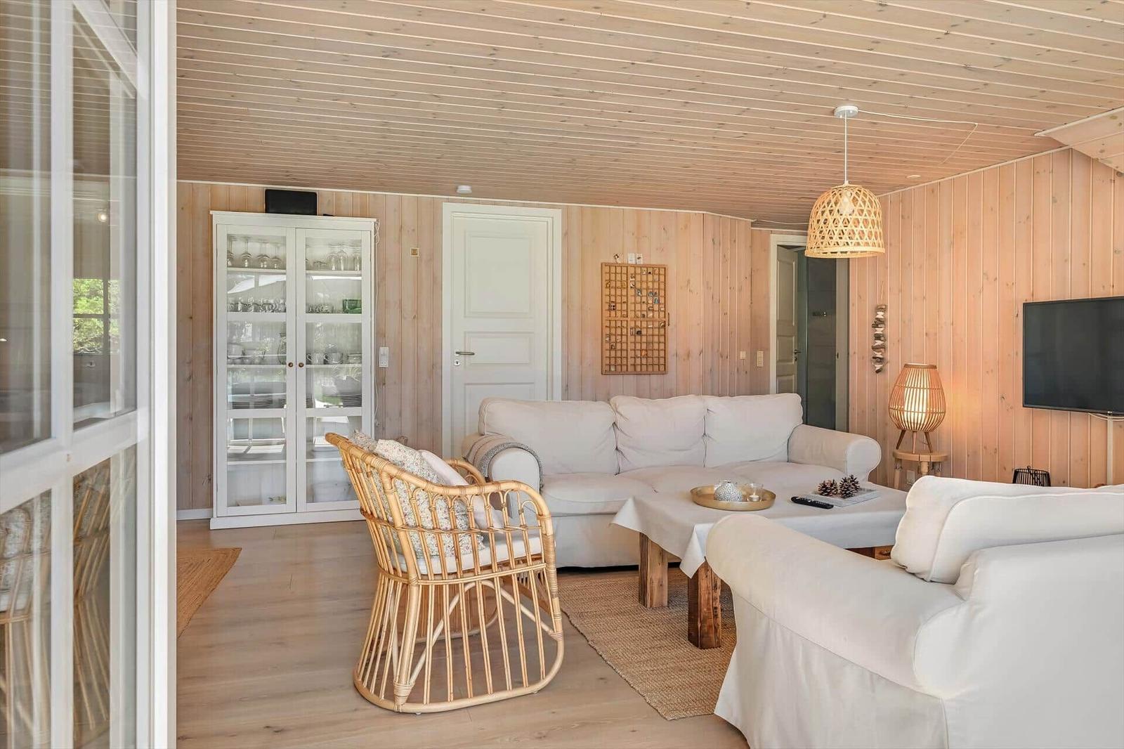 Wohnzimmer mit weißen Sofas, Holzwand und Pendelleuchte.
