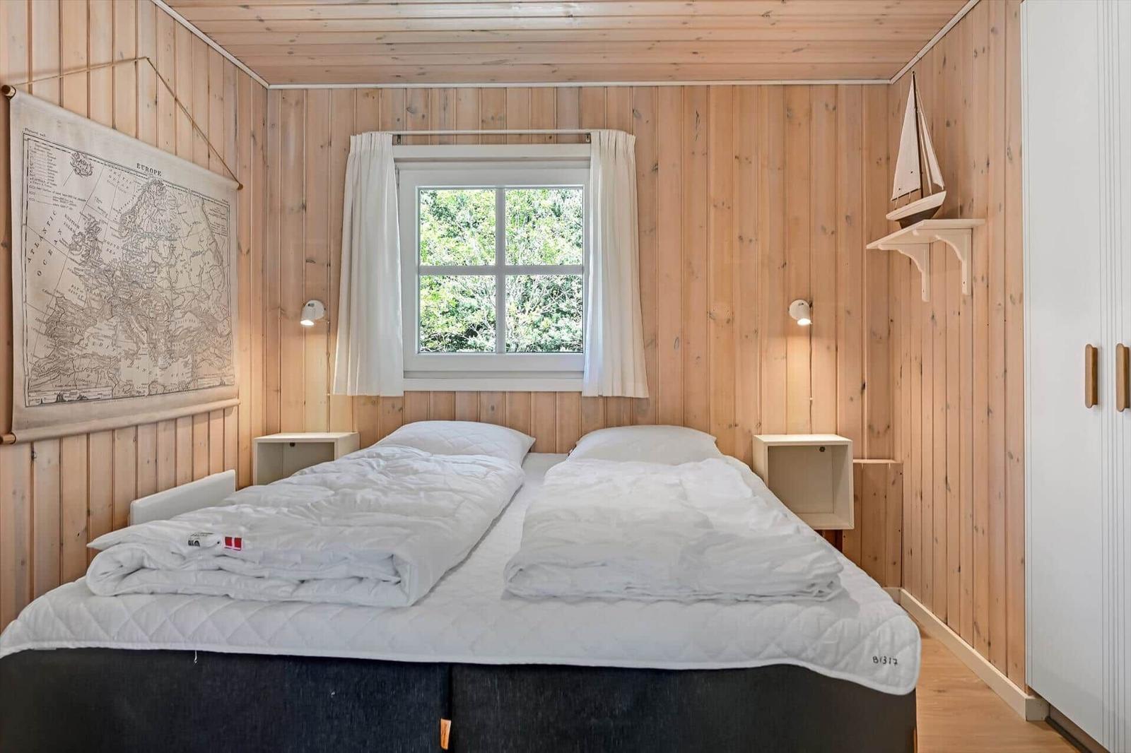 Schlafzimmer mit Holzwand, Bett, Fenster und Karte an der Wand.