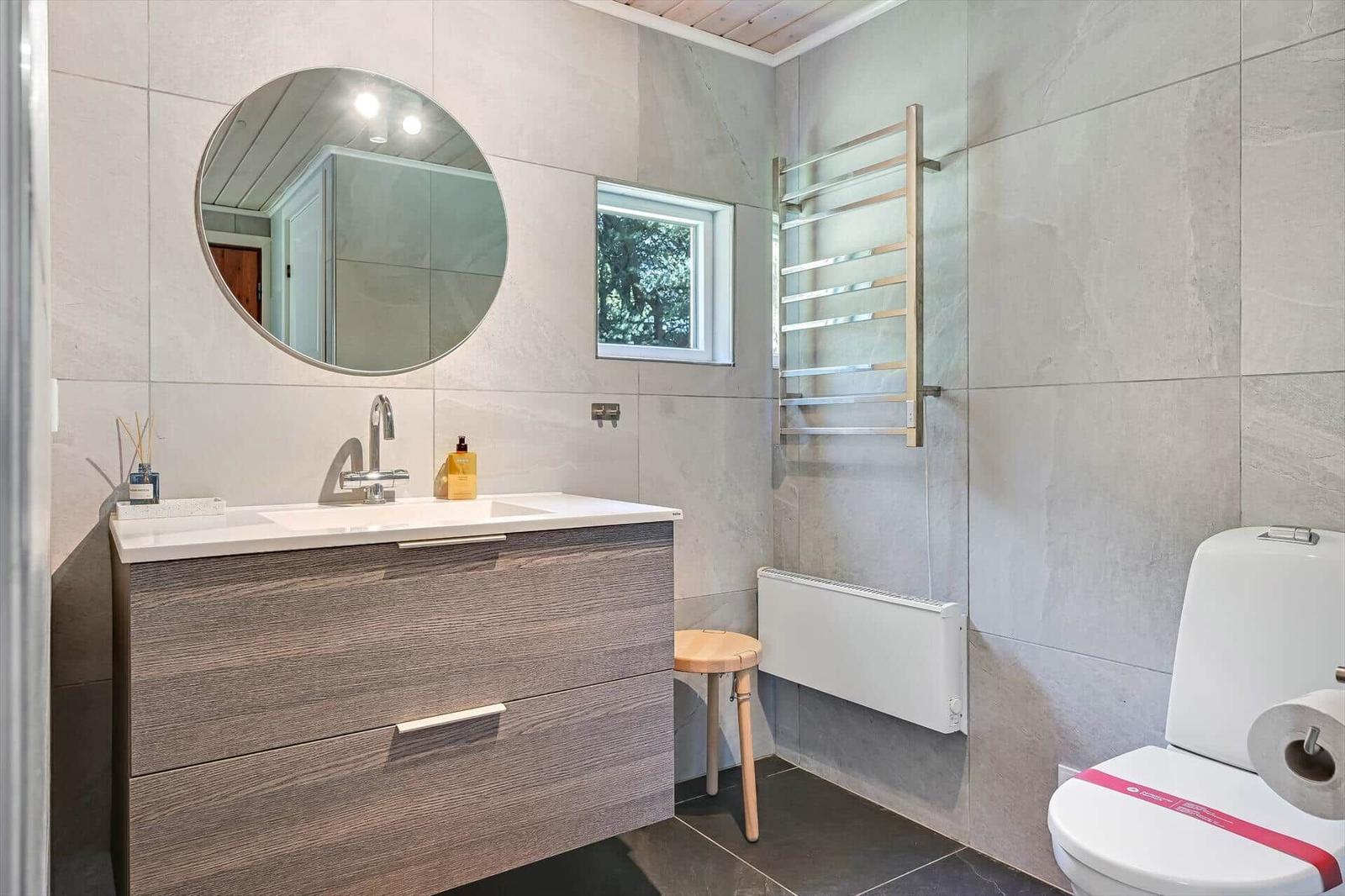 Bad mit Waschbecken, Spiegel, Toilette und Heizkörper.