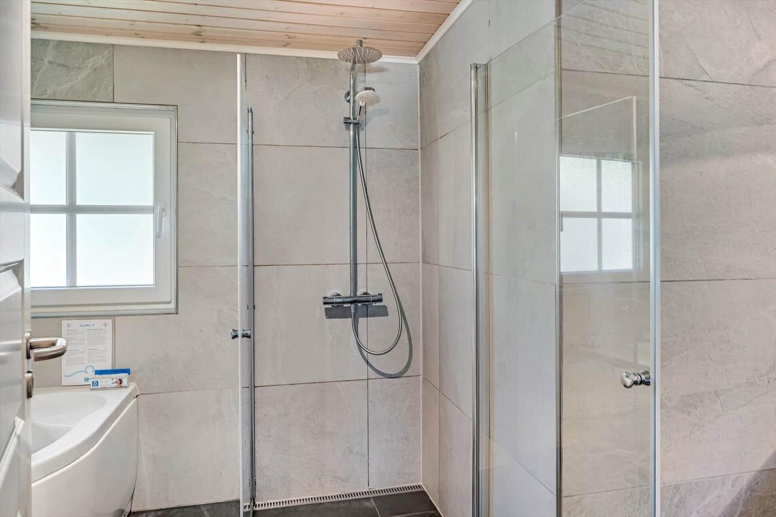 Dusche mit Glaswand, Duschbrause und Fenster