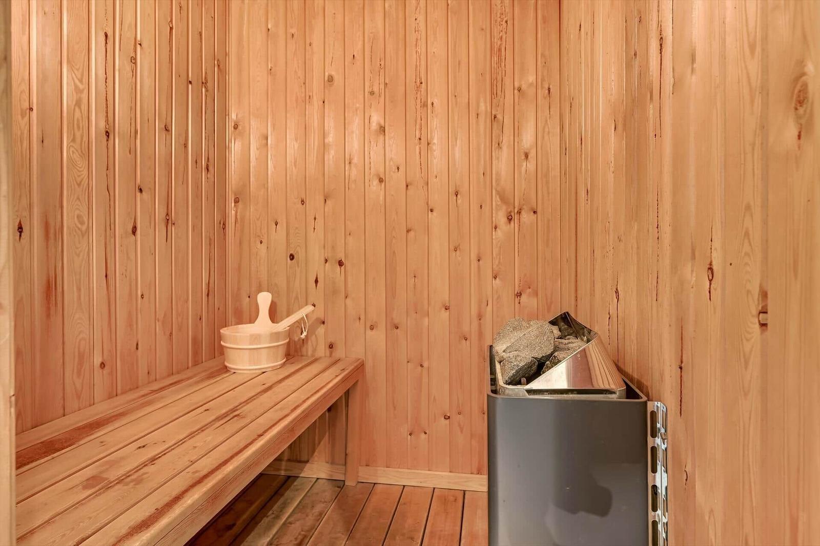 Sauna mit Holzwand, Sitzbank und Steinkiste.