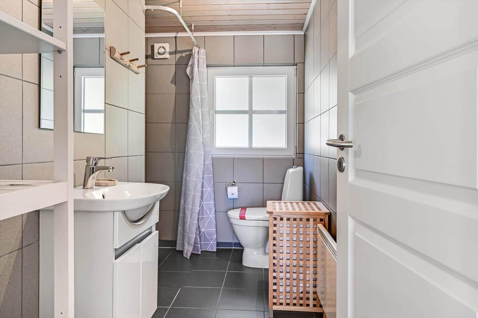 Badezimmer mit Waschbecken, Toilette und Dusche mit Vorhang.
