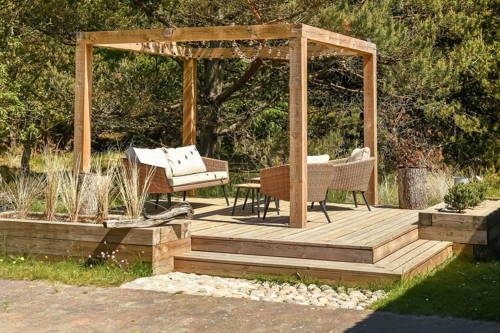 Holzterrasse mit Pavillon, Sitzmöbel und Beleuchtung im Garten