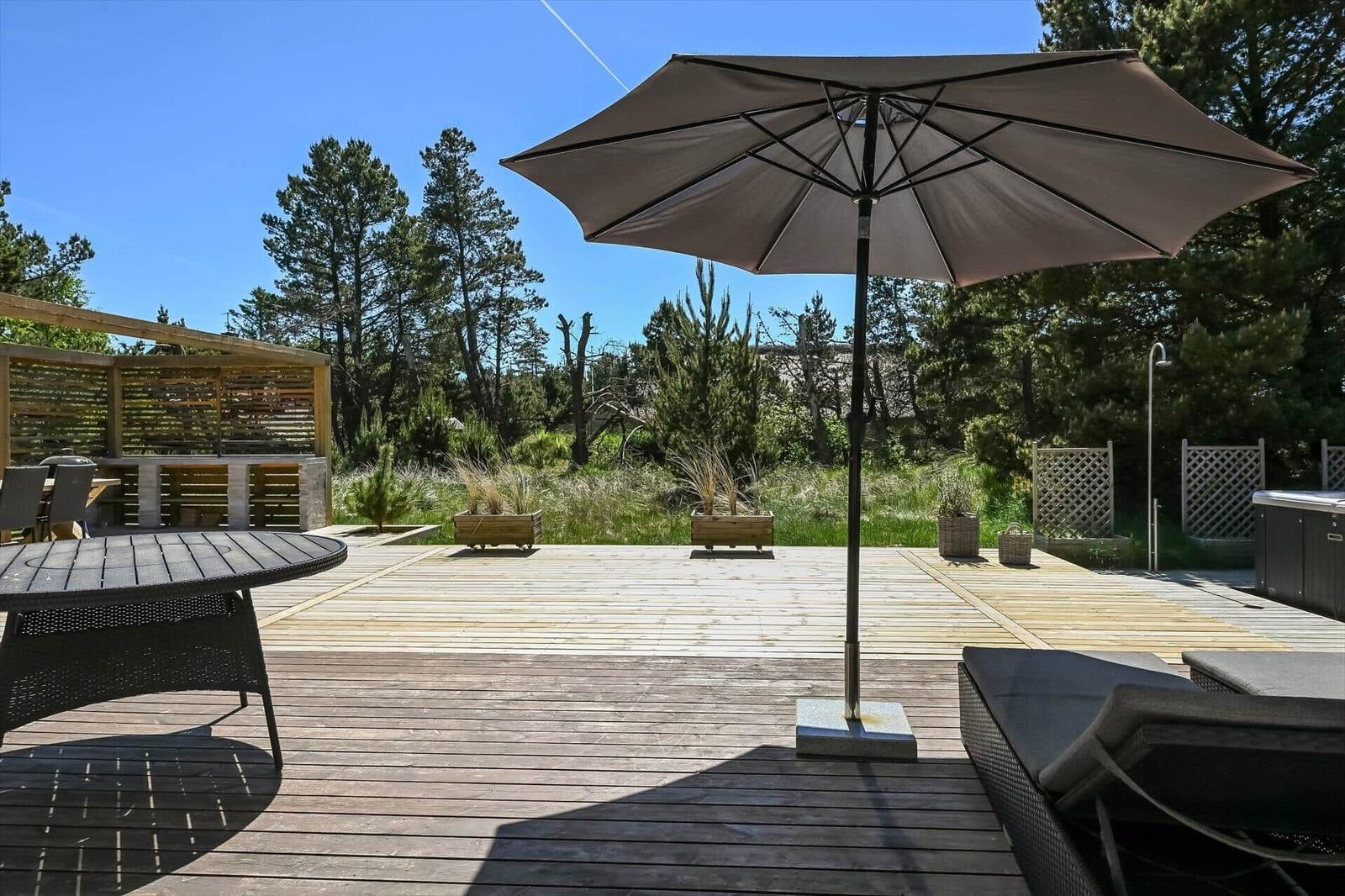 Terrasse mit Sonnenschirm, Sitzgelegenheiten und Gartenbereich.