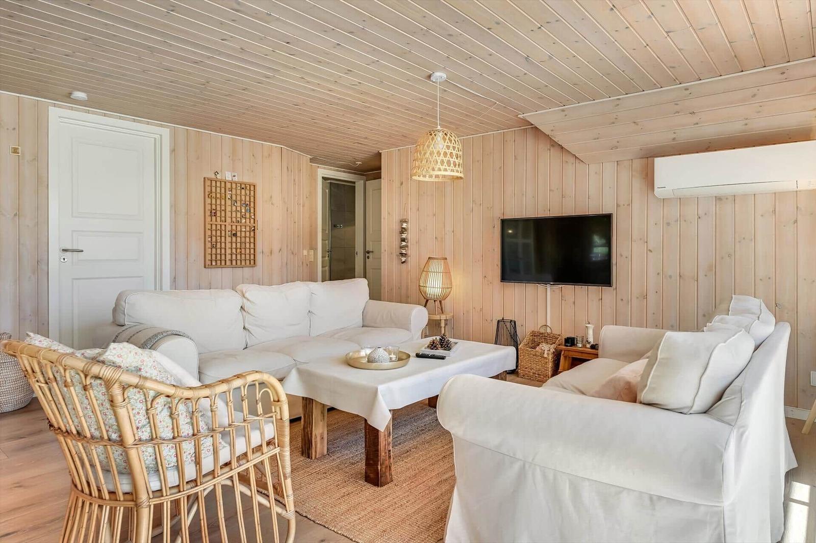 Wohnzimmer mit weißen Sofas, Holzwand und Fernseher.