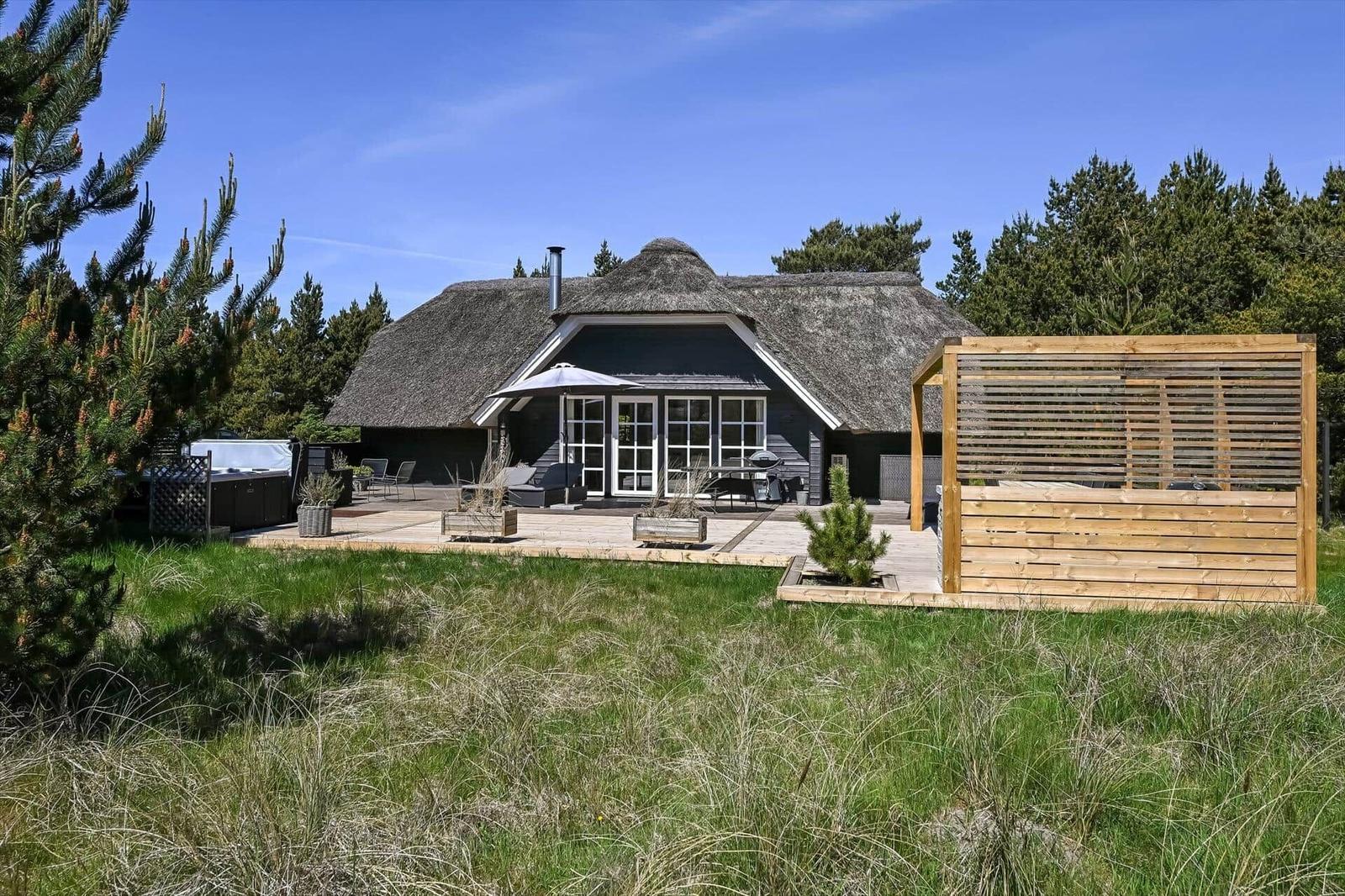 Haus mit Strohdach, Terrasse und Holzgeländer im Grasland.