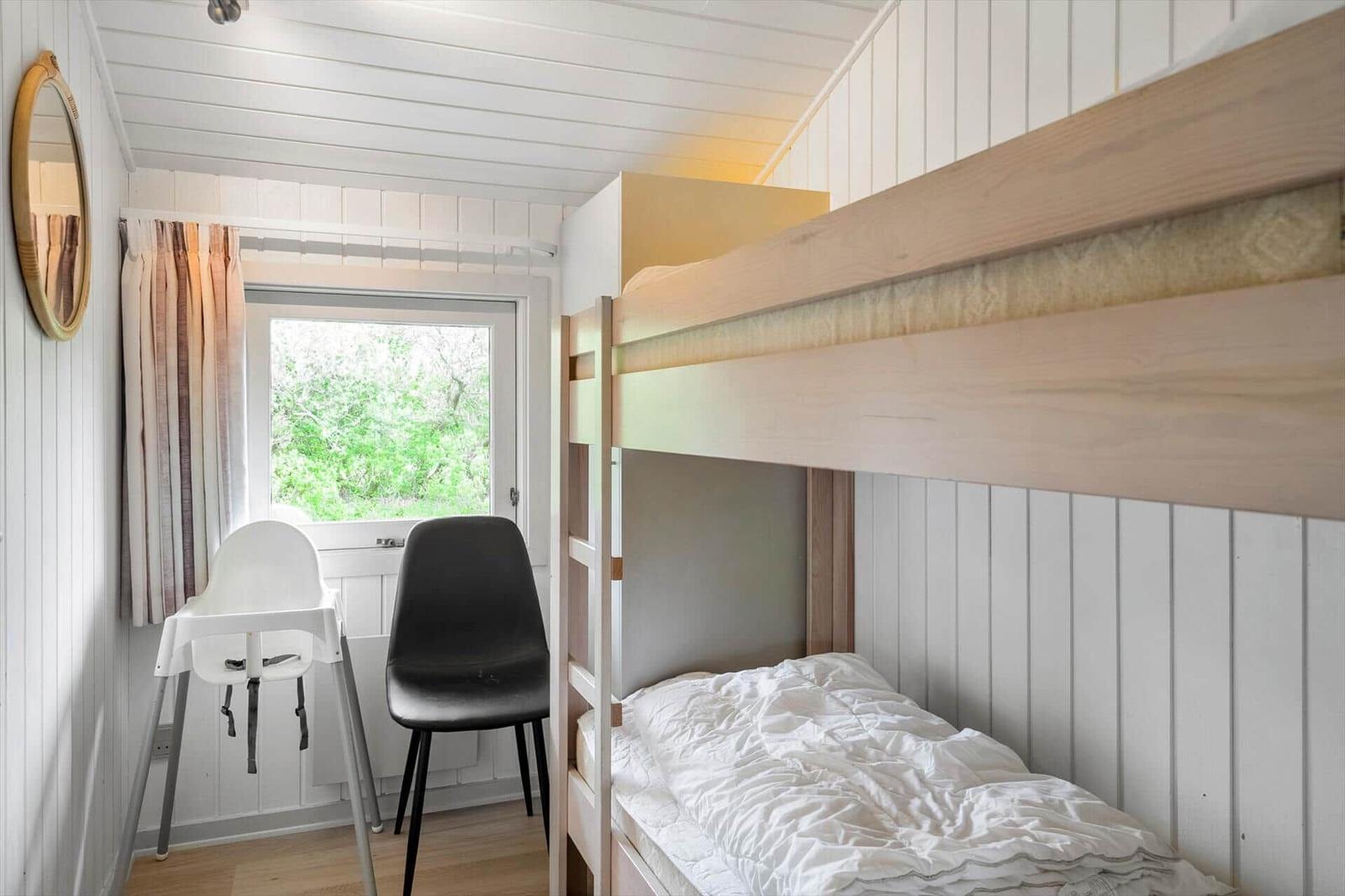 Zimmer mit Doppelstockbett, Fenster und Stühlen.
