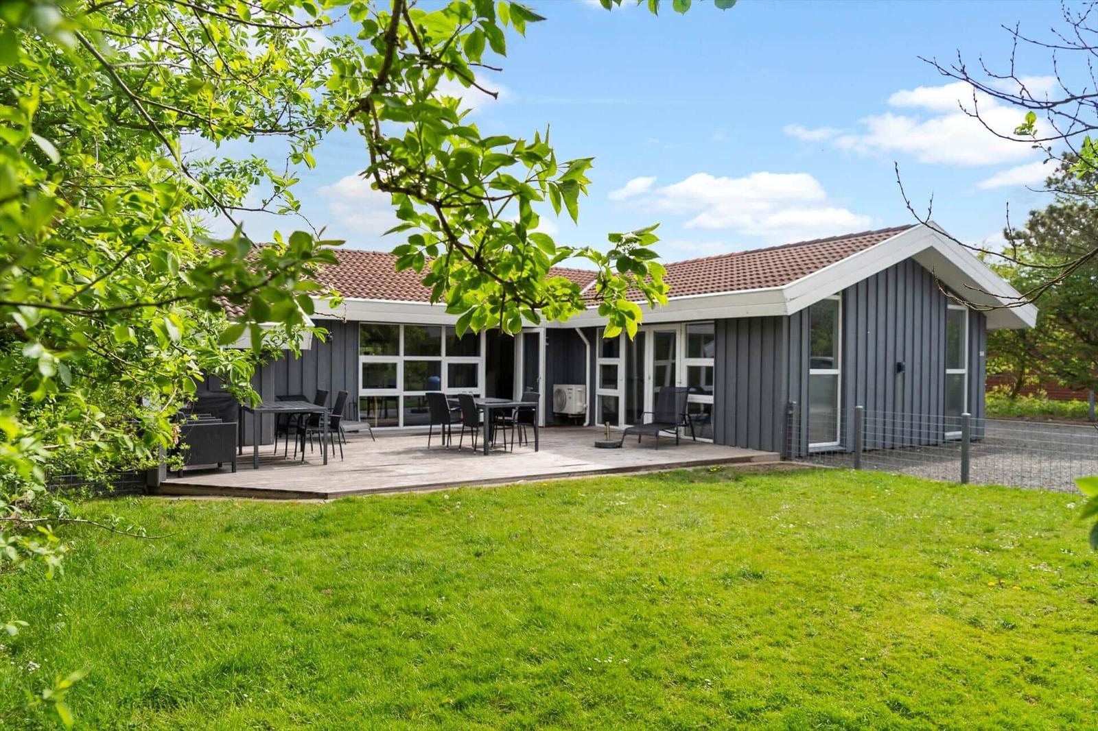 Moderne Villa mit Terrasse und Garten. Außenbereich mit Tisch und Stühlen.