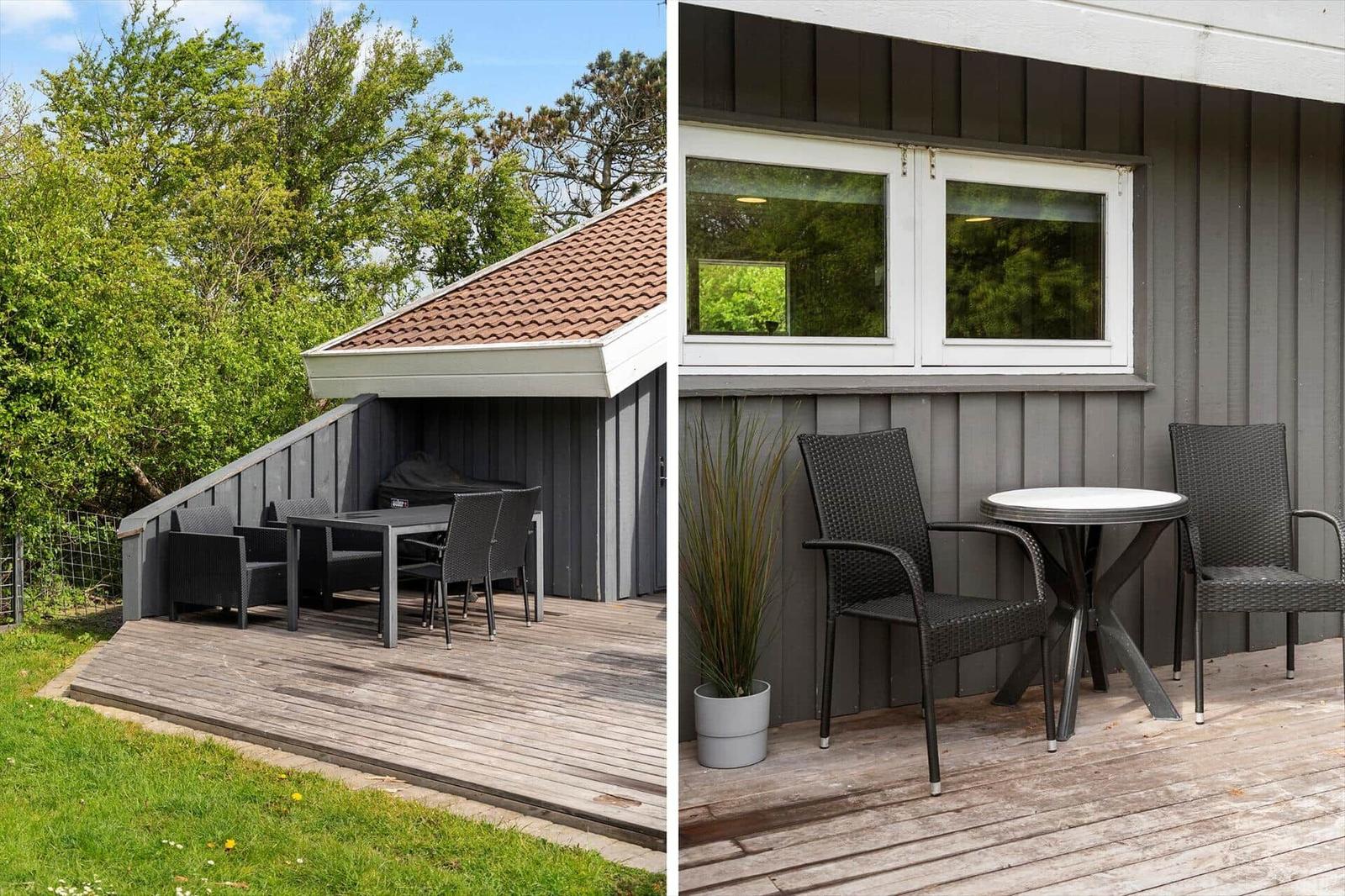Terrasse mit Tisch und Stühlen, Grillbereich und Pflanze vor grauem Holzhaus