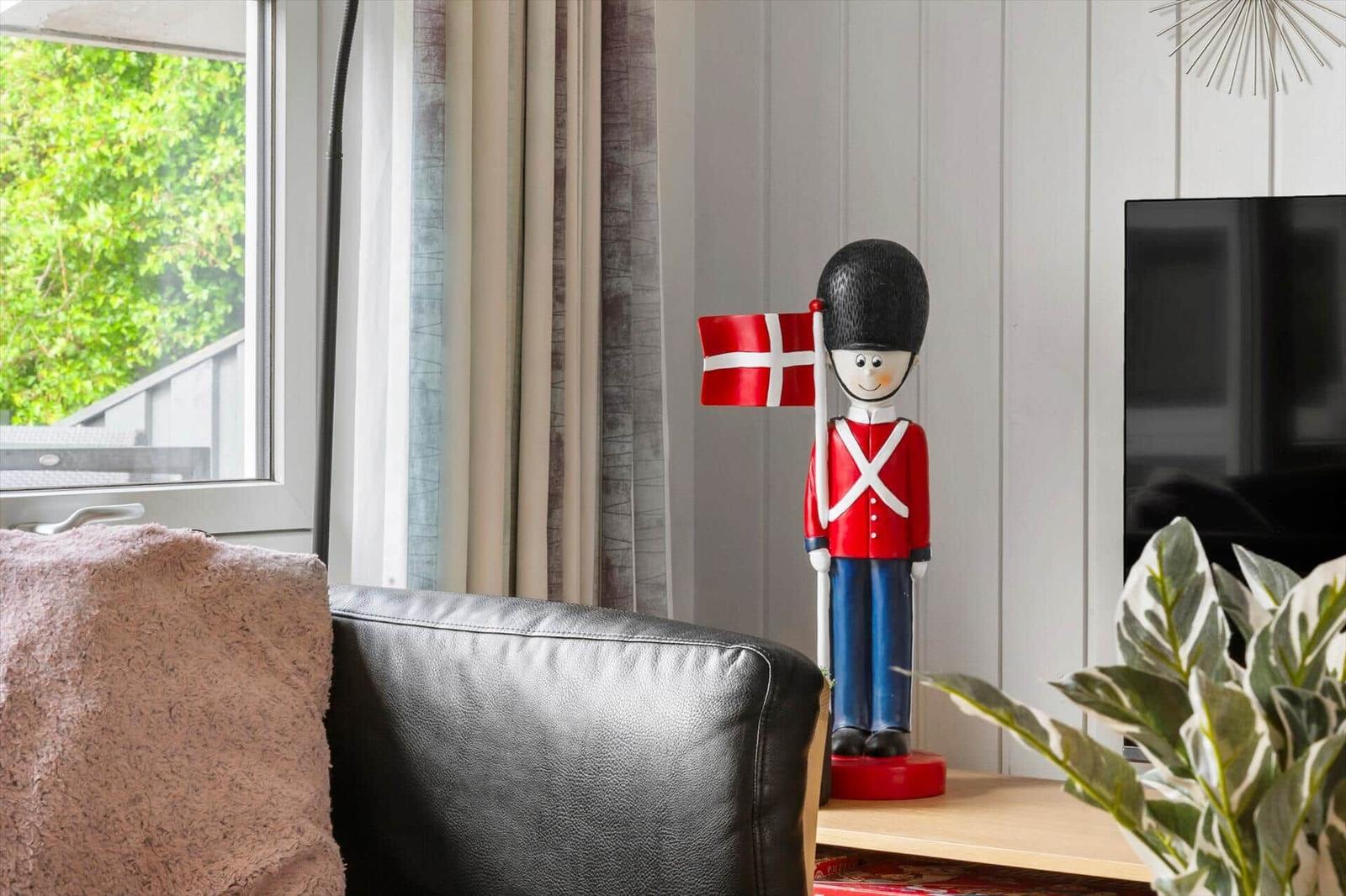 Ein dekorativer Soldatenfigur mit dänischer Flagge steht auf einem Tisch neben einem Sofa.
