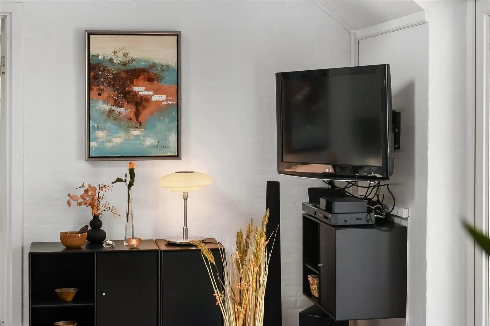 Wohnzimmer mit Fernseher, Beistelltisch und Wandbild.