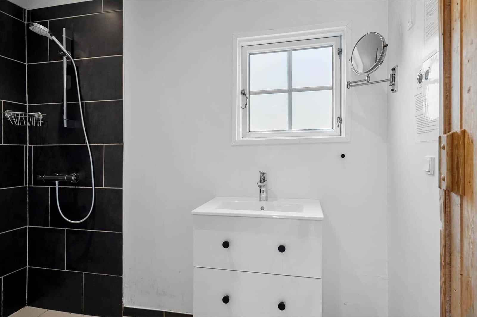 Badezimmer mit Dusche, Waschbecken und Fenster