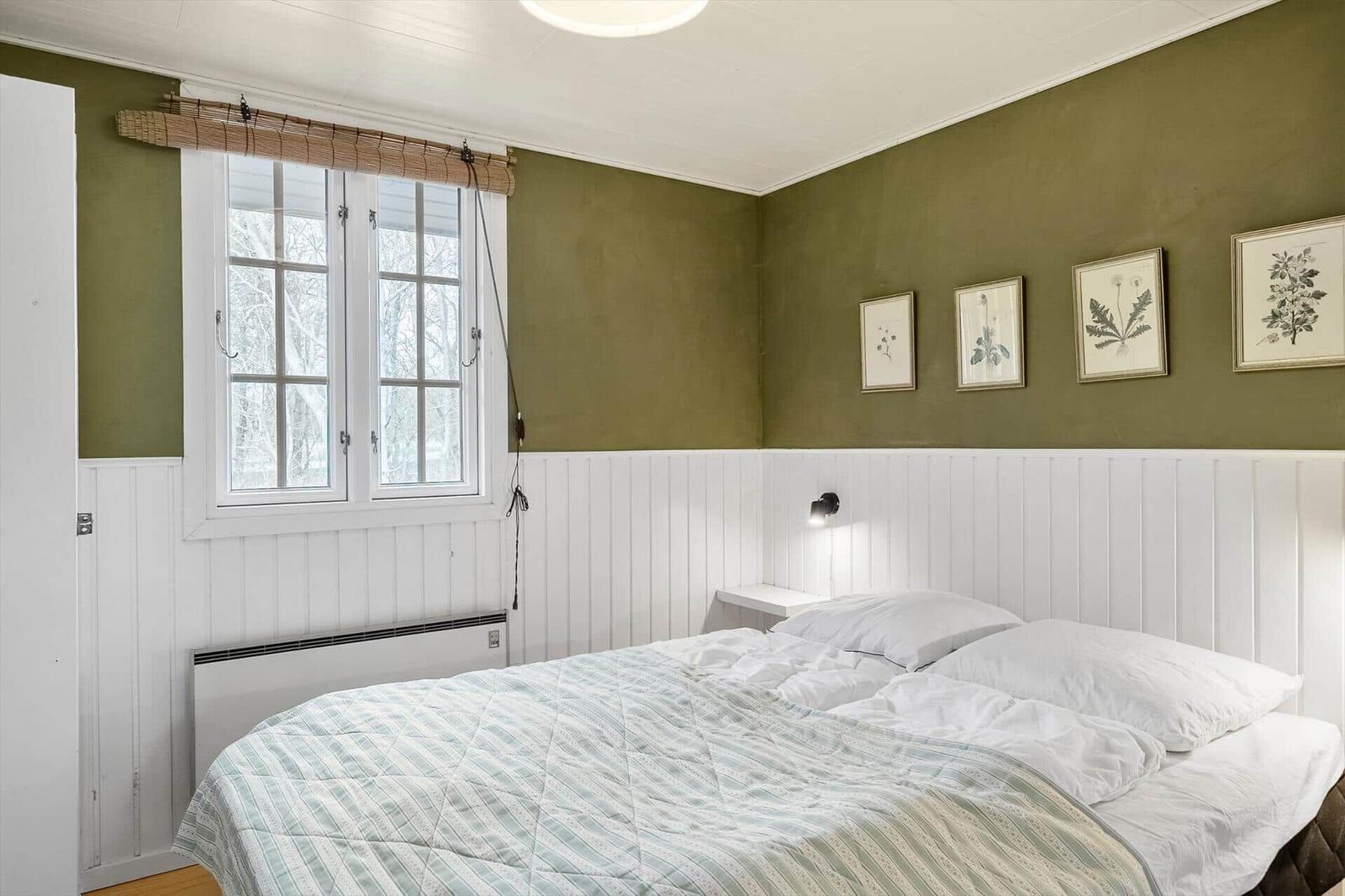 Schlafzimmer mit Bett, Fenster und Wandbildern.