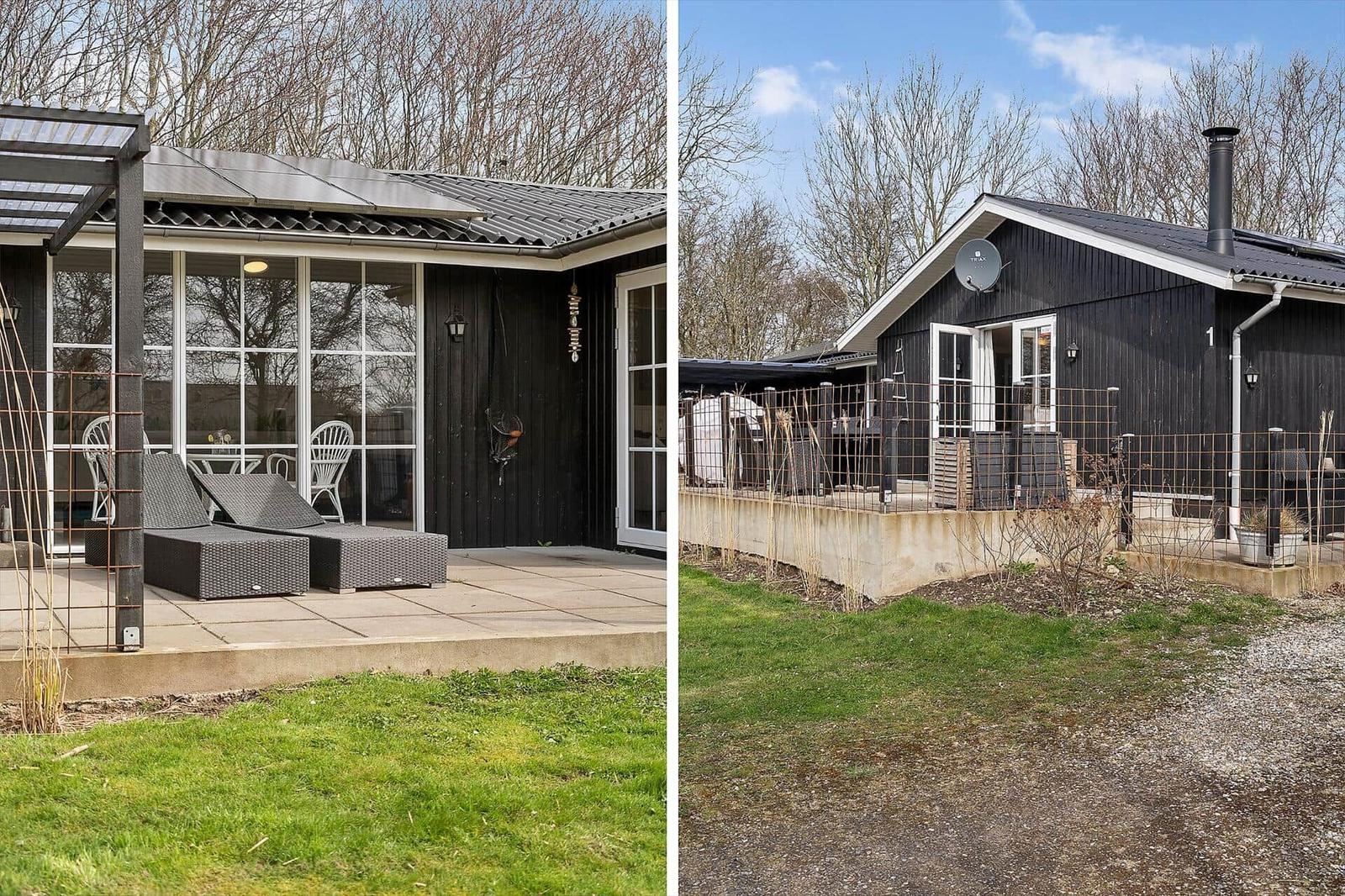 Schwarzes Holzhaus mit Terrasse, Garten und Satellitenantenne. Außenbereich mit Gartenmöbeln.