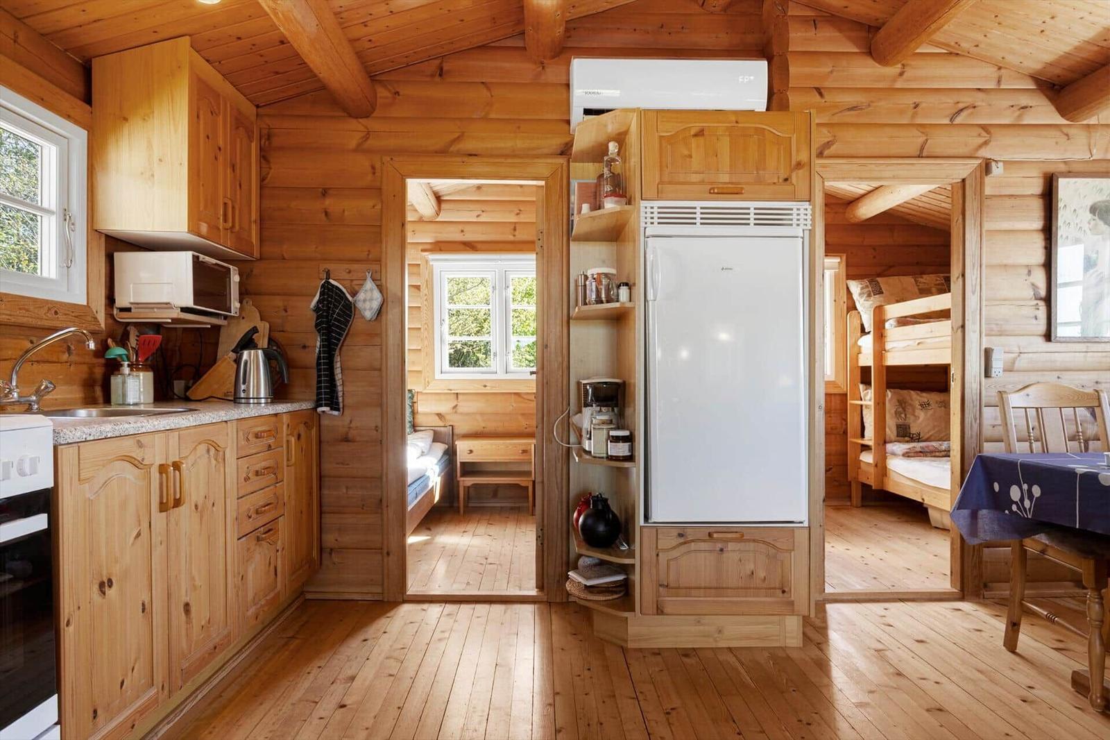 Küche mit Kühlschrank, Mikrowelle und Holzmöbel. Blick in Schlafzimmer mit Doppelbett.