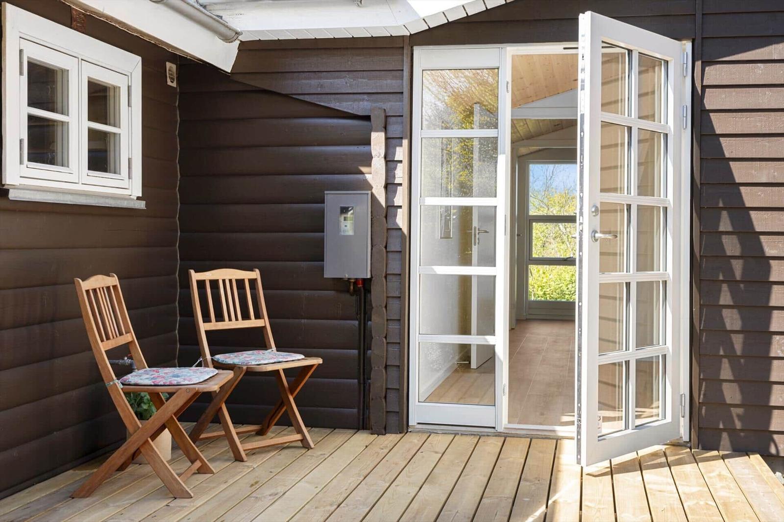 Terrasse mit zwei Holzstühlen und Glastüren zum Haus.