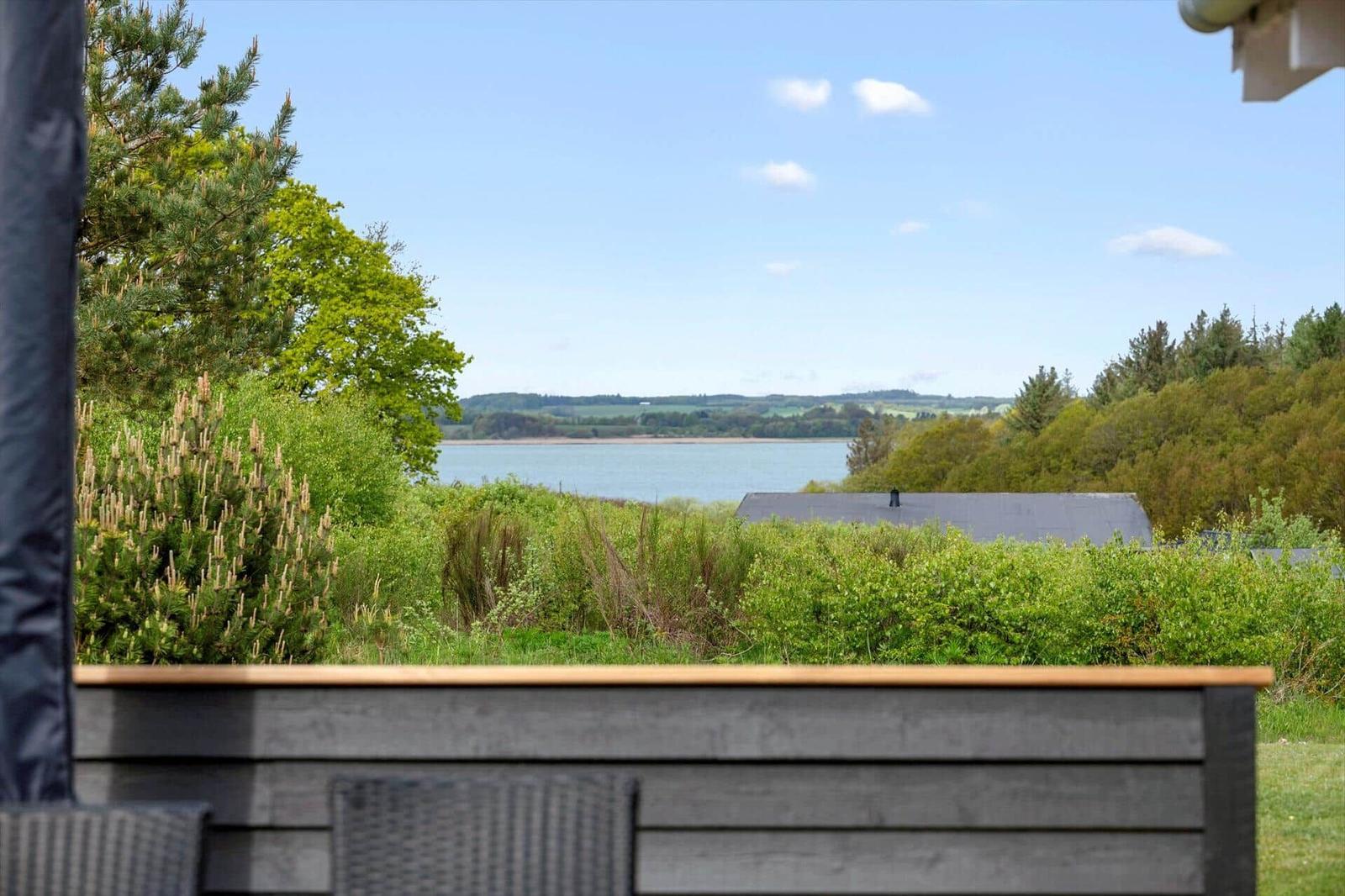 Terrasse mit Blick auf einen See und grüne Landschaft.