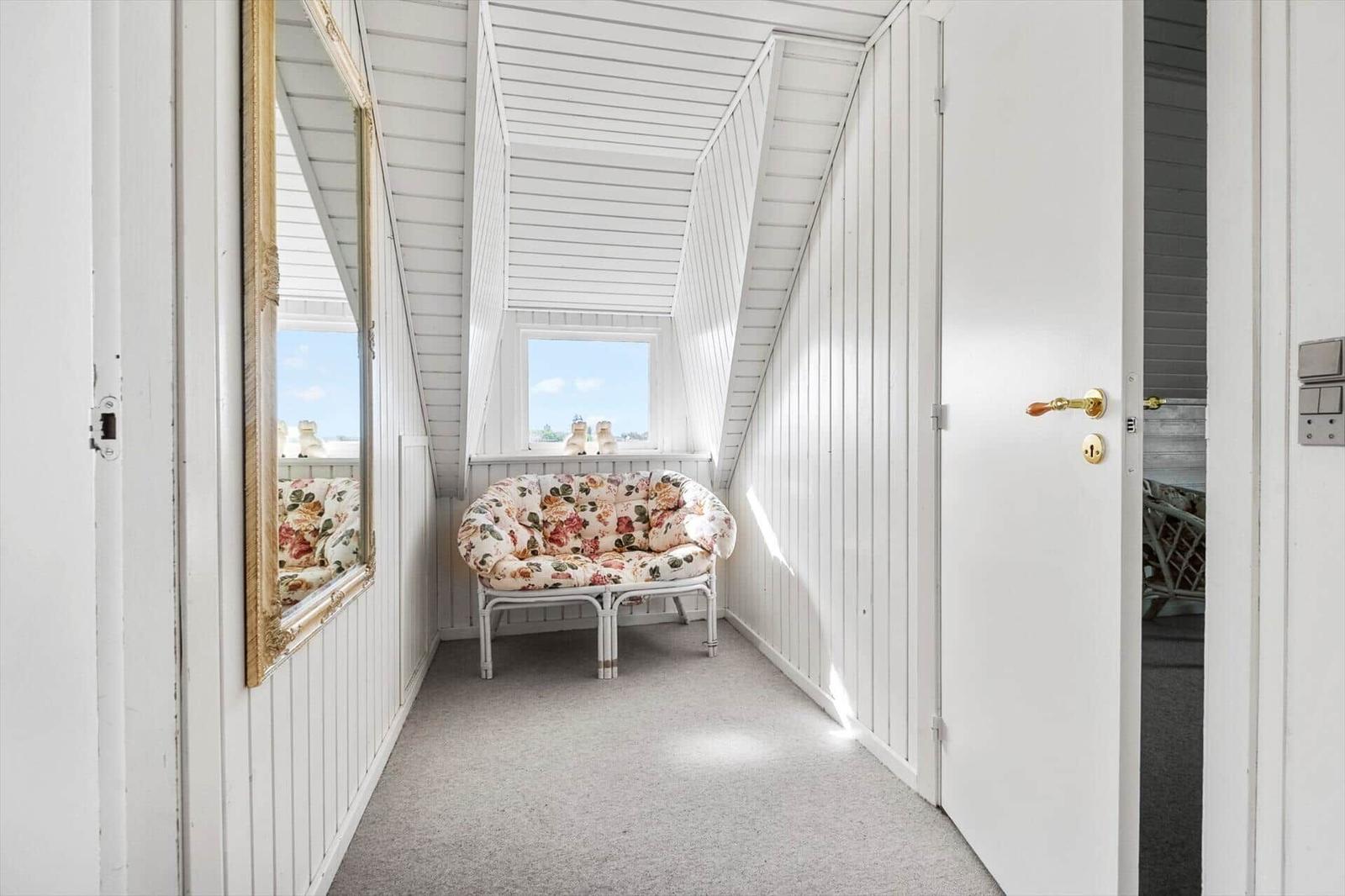 Hallway with seating, mirror, and door. Skylight with view outside.