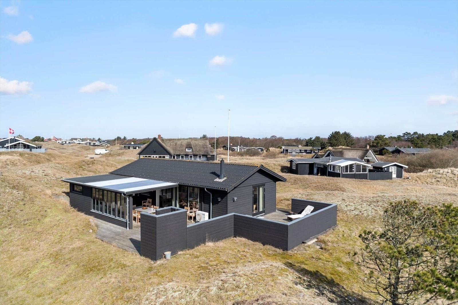 Moderne Villa mit Terrasse und Grillplatz auf grüner Wiese.