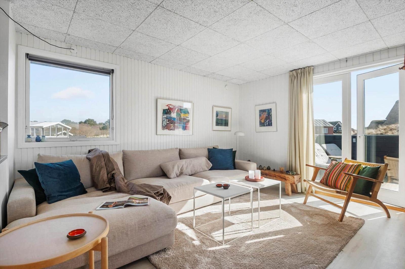 Wohnzimmer mit Sofa, Sitzgelegenheit und Blick auf Balkon.