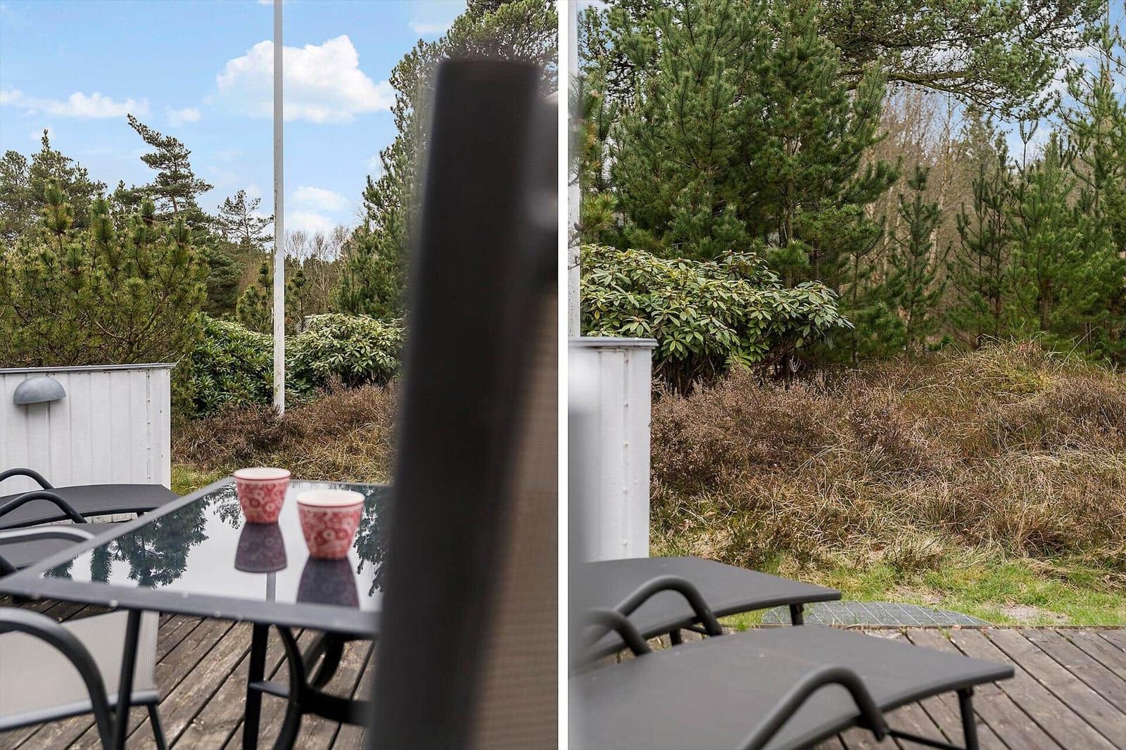 Terrasse mit Tisch und Stühlen, Blick auf Wald und Himmel.