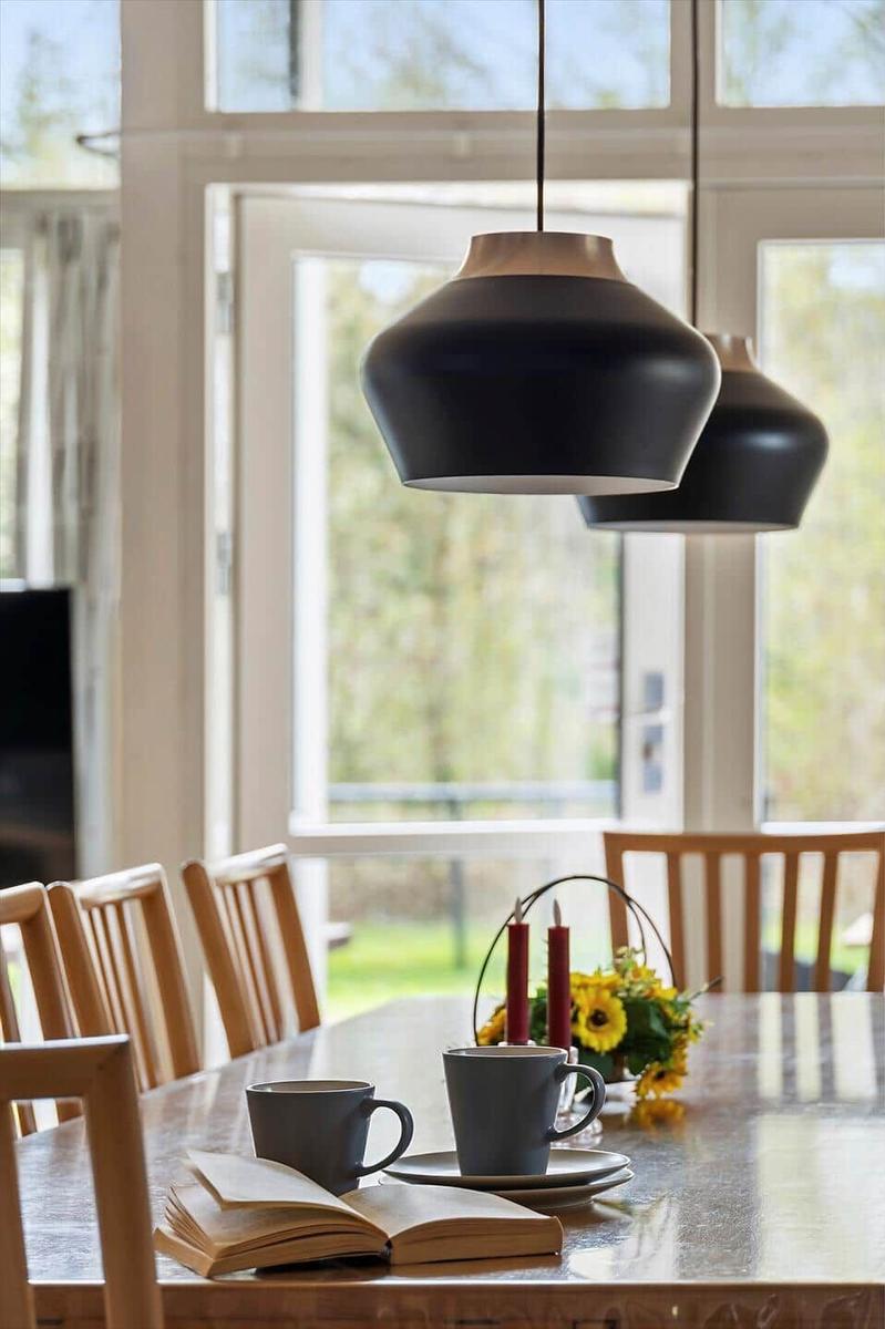 Esstisch mit Stühlen, Kerzen und Blumen. Hängelampen über dem Tisch.