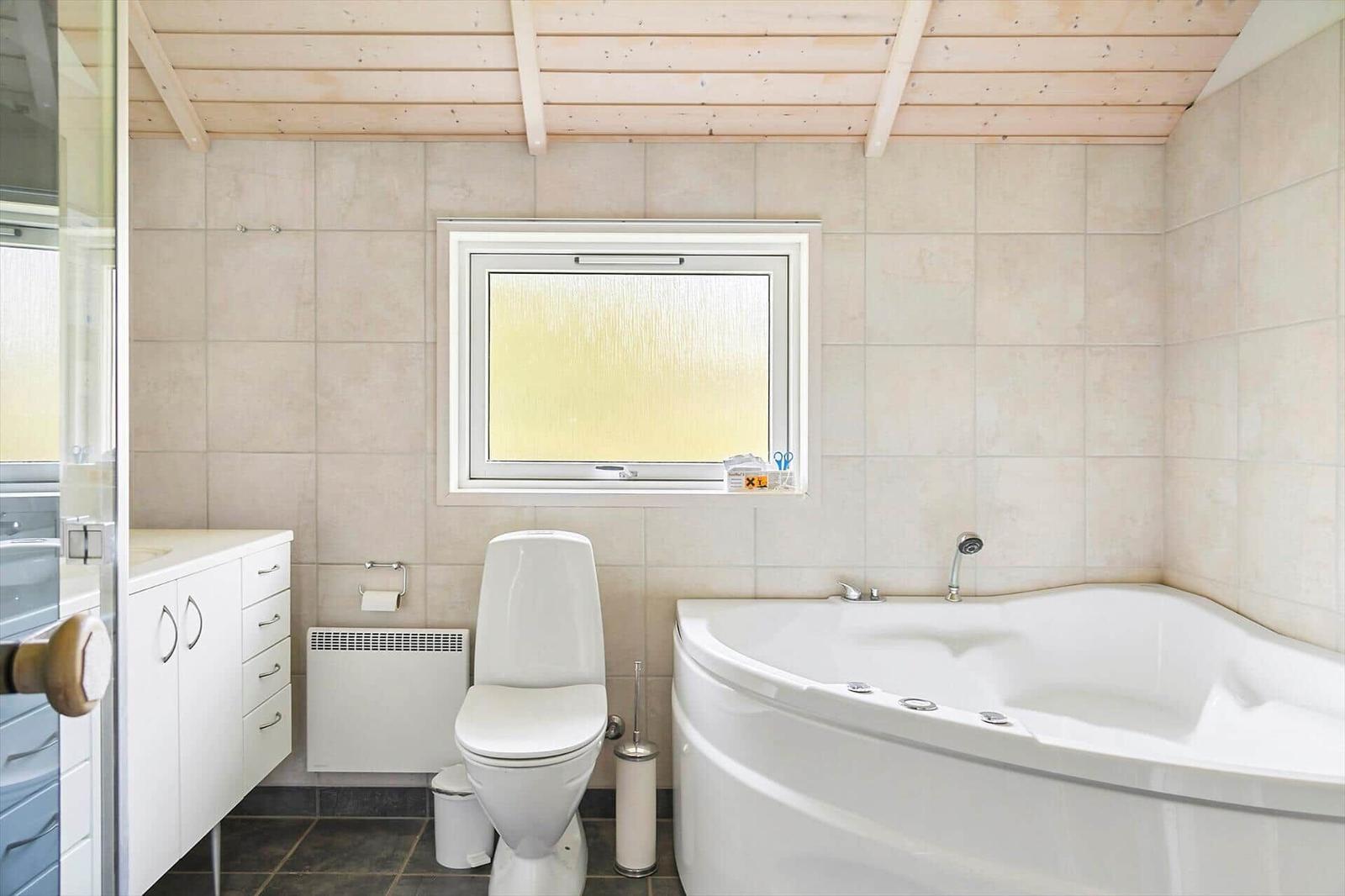 Bad mit Dusche, Toilette und Whirlpool-Badewanne.