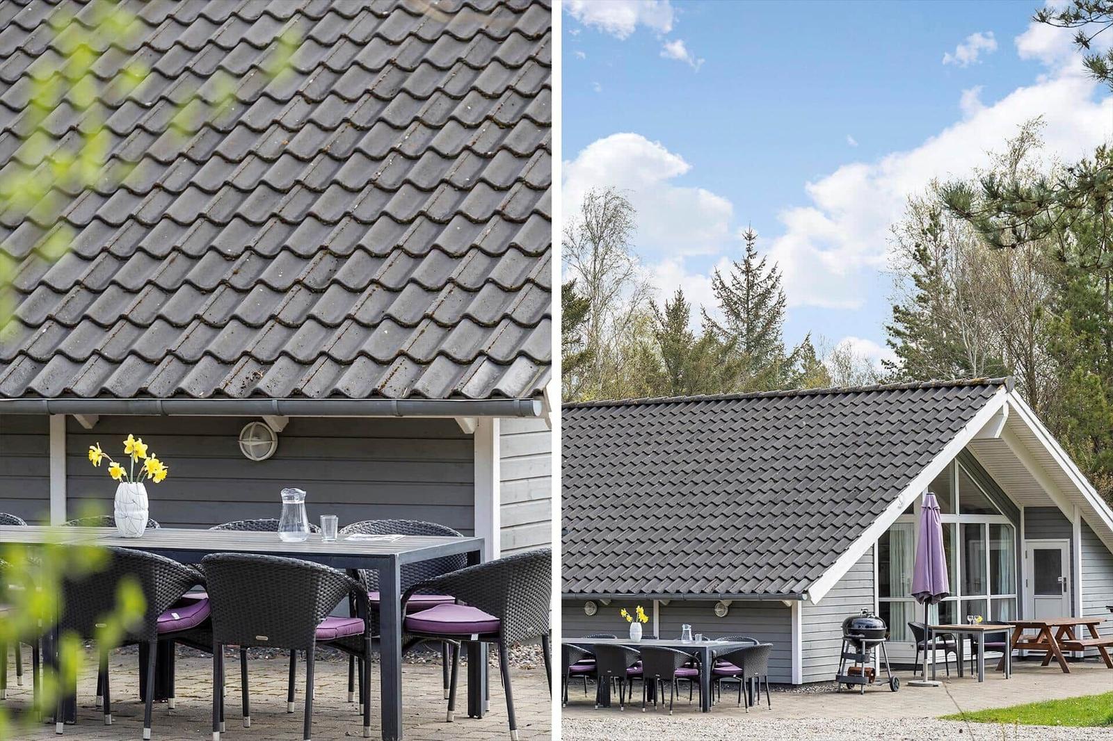 Haus mit Terrasse, Tisch, Stühlen und Grill unter einem Dach mit Schieferziegeln.