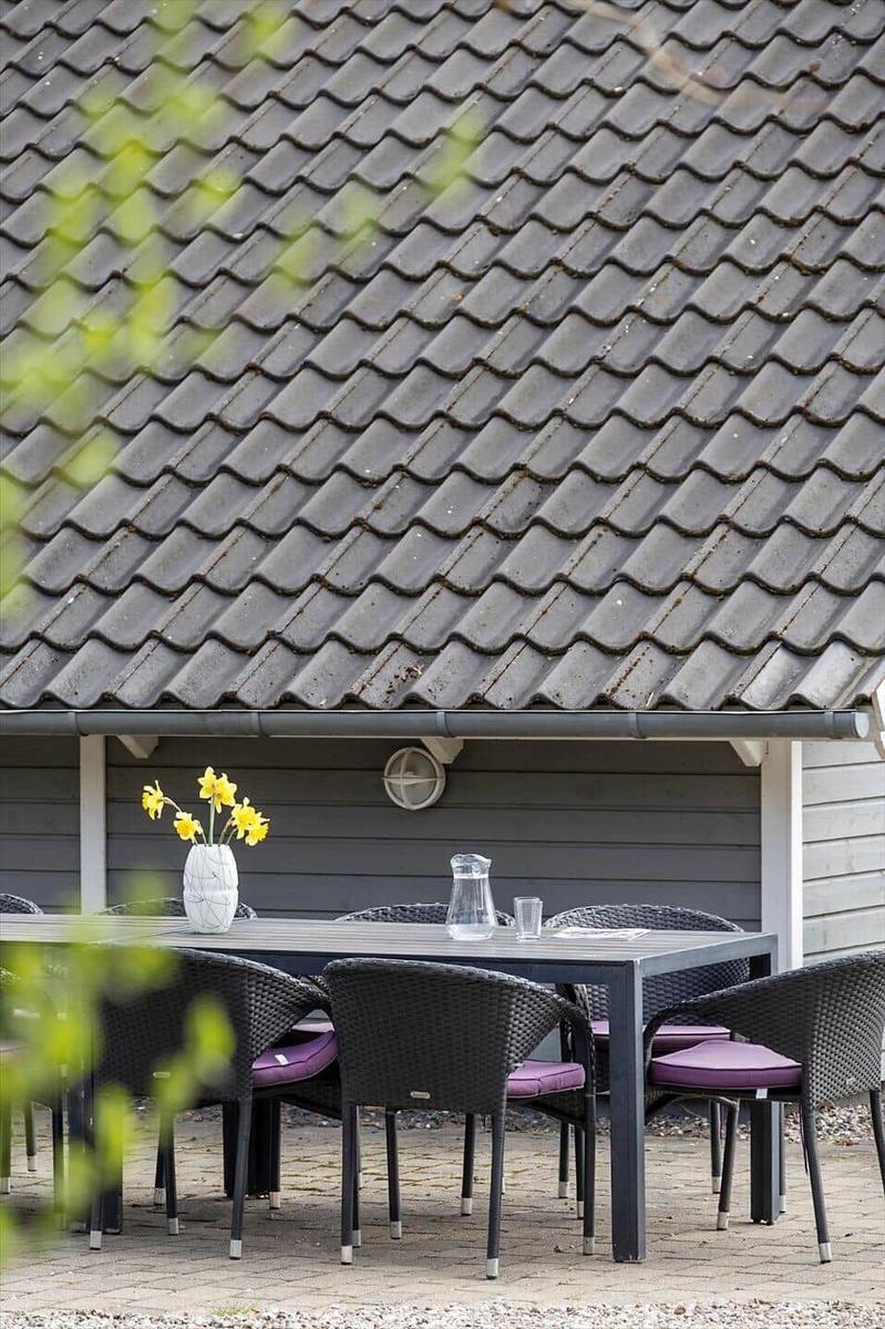 Außenterrasse mit Tisch, Stühlen und Blumen unter Dach