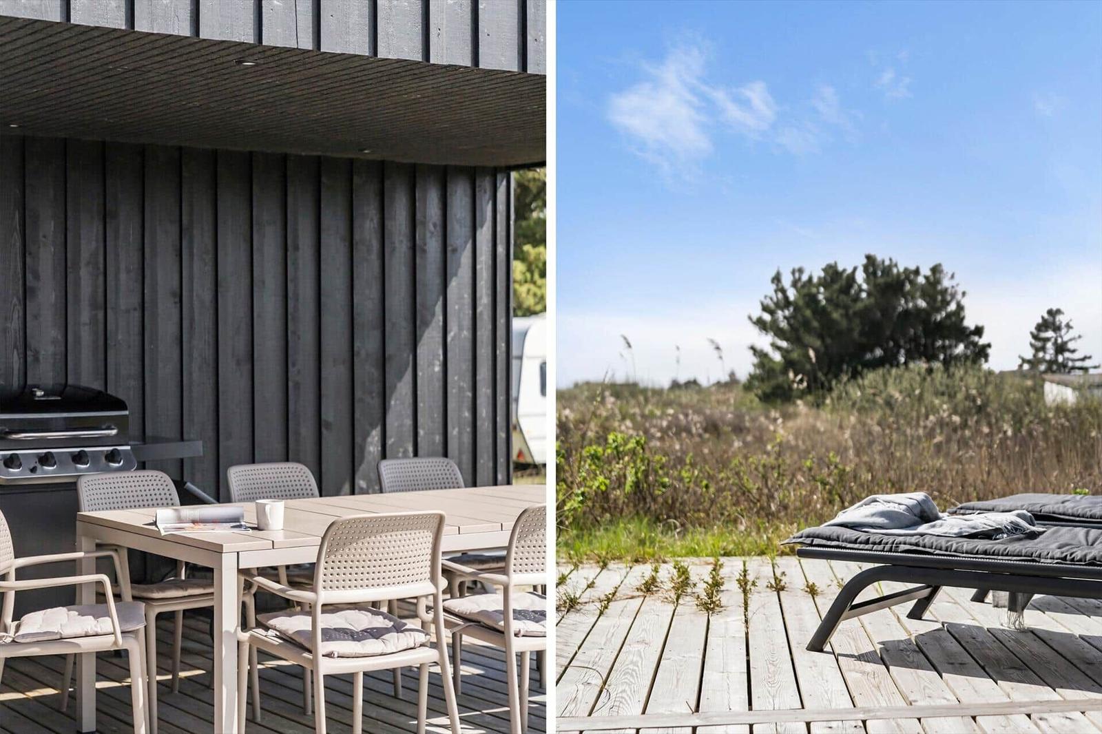 Terrasse mit Grill und Tisch. Holzterrasse mit Liegen und Blick auf Grasland.