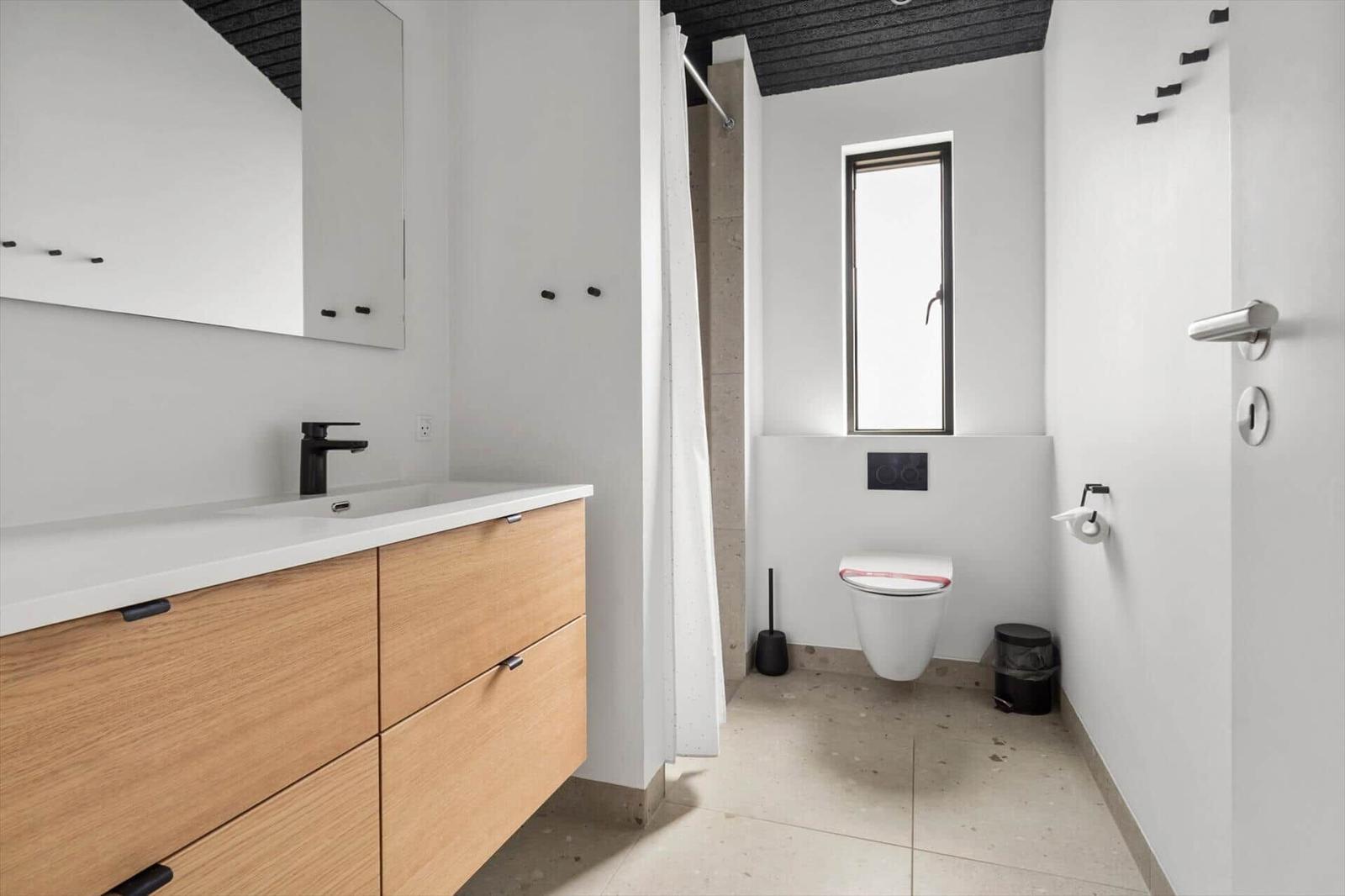 Badezimmer mit Waschbecken, Dusche und Toilette. Moderne Einrichtung mit Holzschrank.