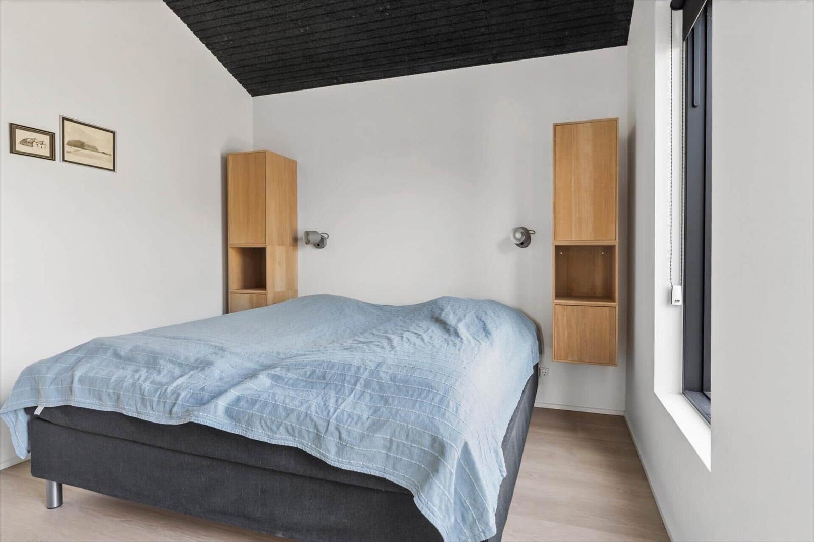 Schlafzimmer mit Bett, Holzregalen und Fenster