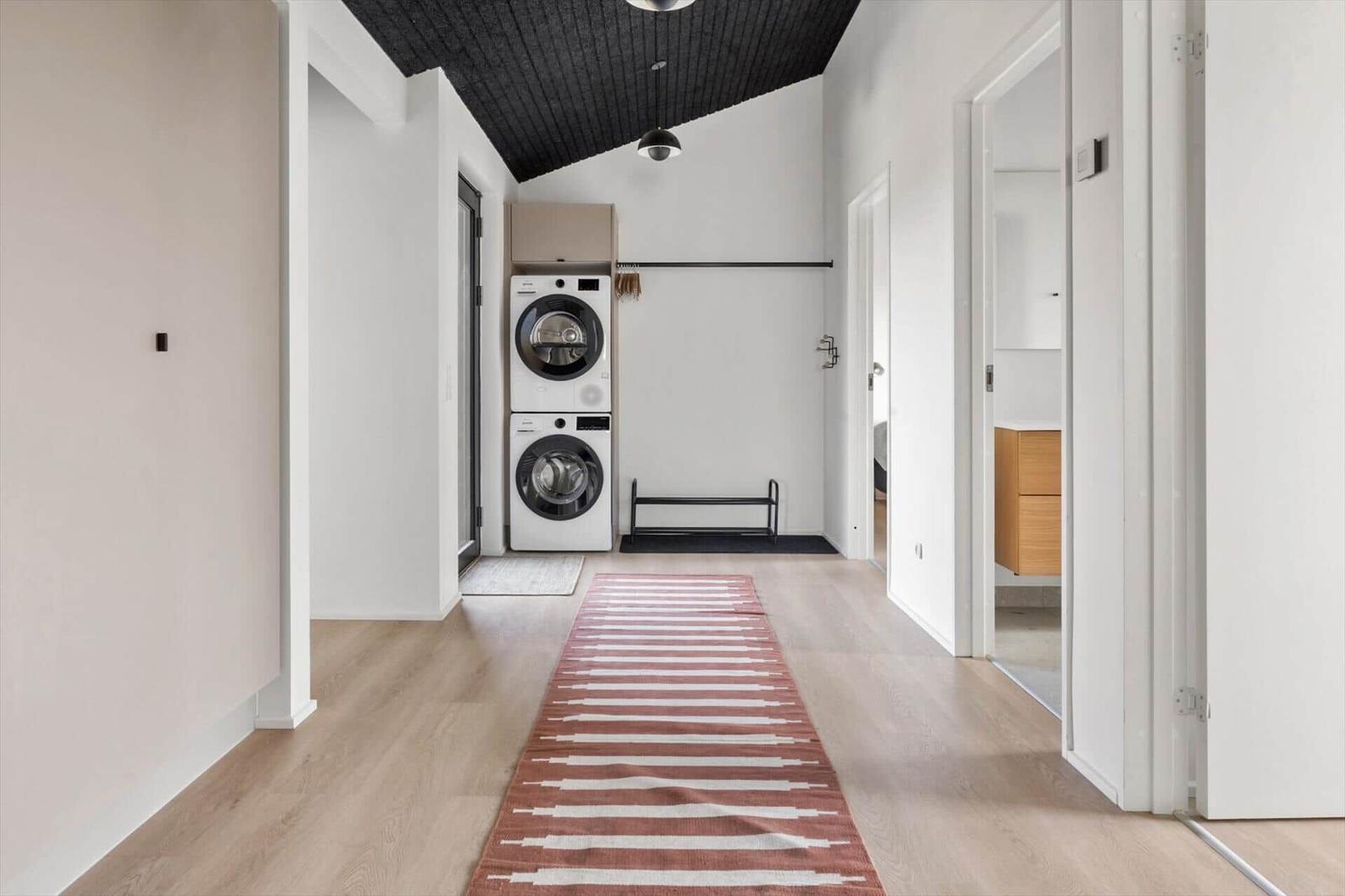 Flur mit Waschmaschine, Teppich und schwarzem Deckenventilator.
