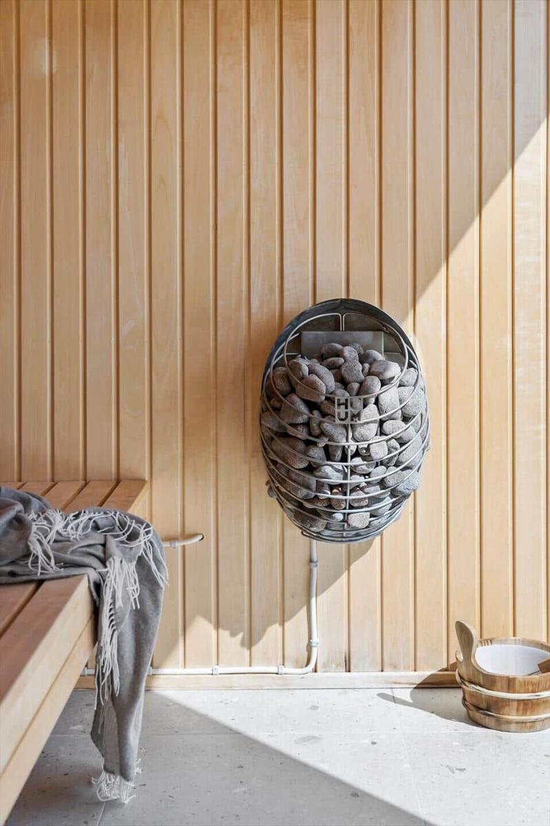 Sauna mit Holzwand, Steinbehälter und Holzbank mit Decke.