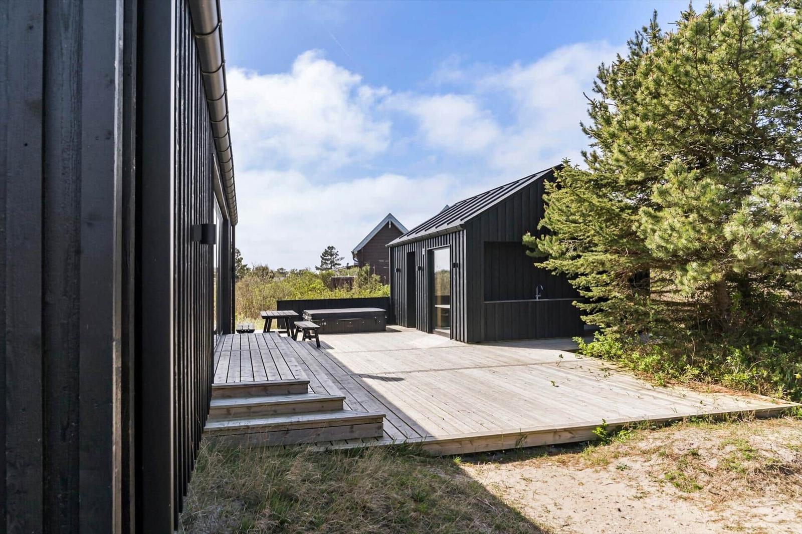 Moderne Holzhütte mit Terrasse, Grill und Blick auf die Natur.