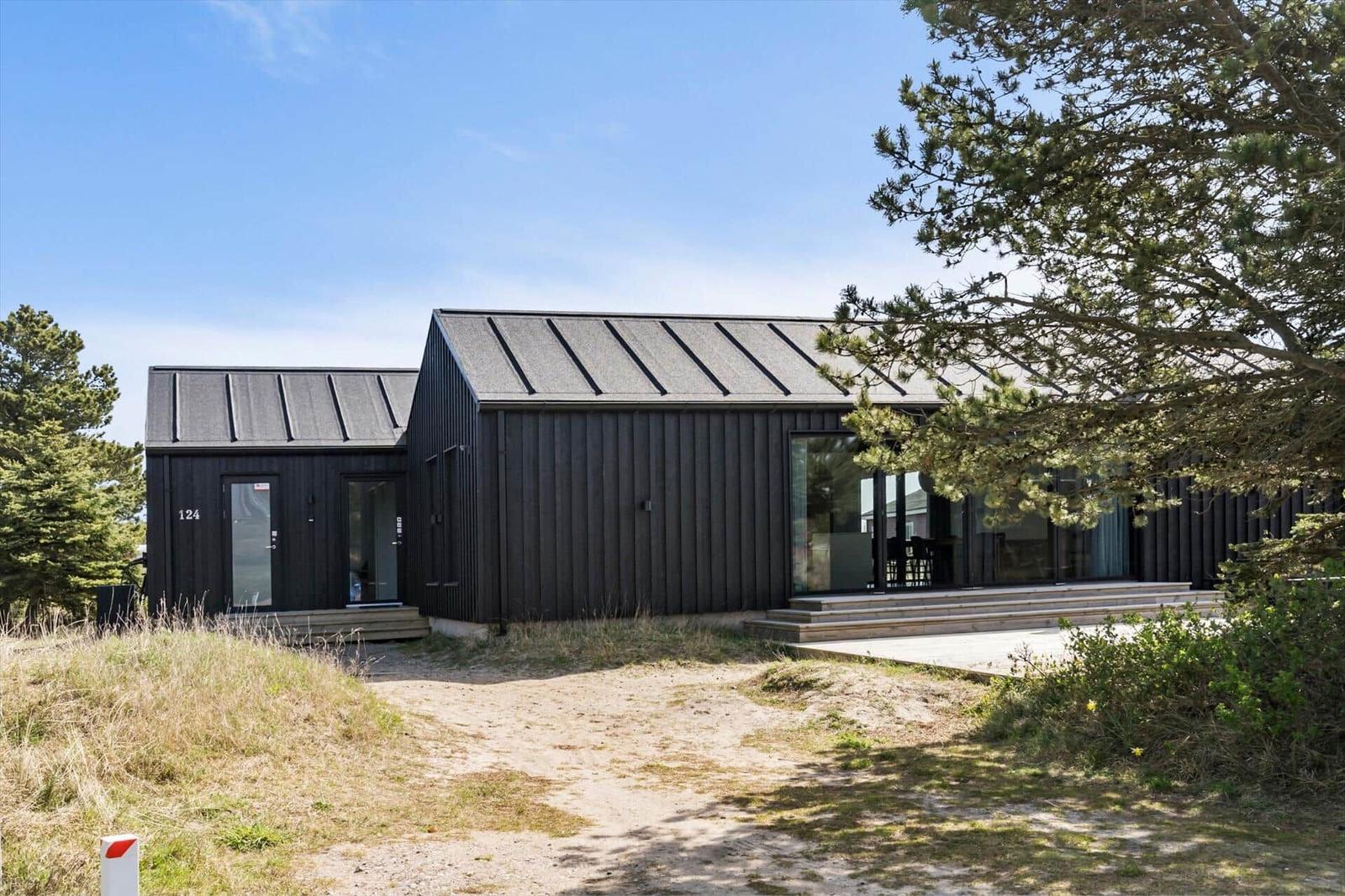 Moderne schwarze Hütte mit Glasfront und Terrasse im Grasland