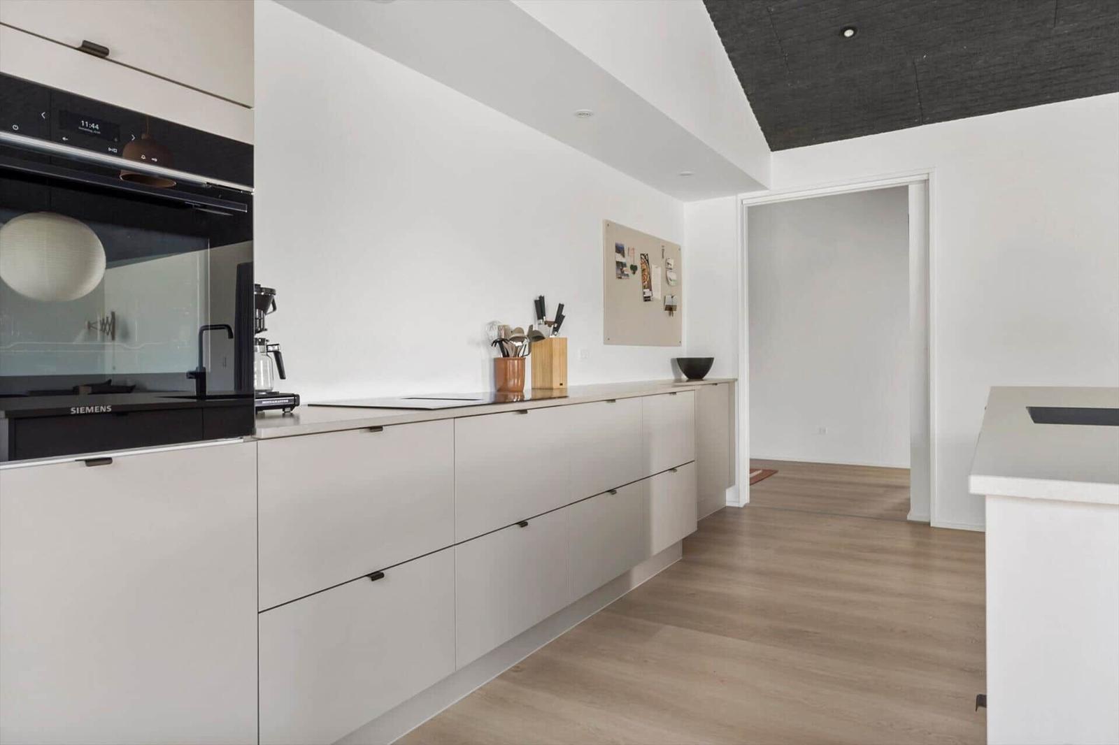 Moderne Küche mit weißen Schränken, Edelstahlgeräten und Holzboden.