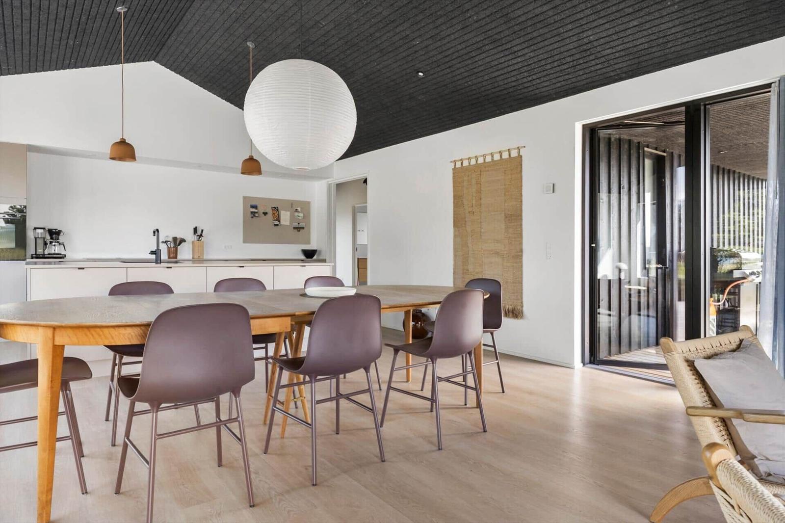 Esszimmer mit Holztisch, Stühlen und Glasfront zur Terrasse.