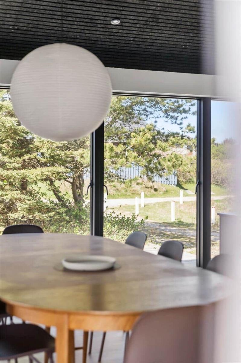 Esszimmer mit Tisch, Stühlen und großen Fenstern zur Außensicht.