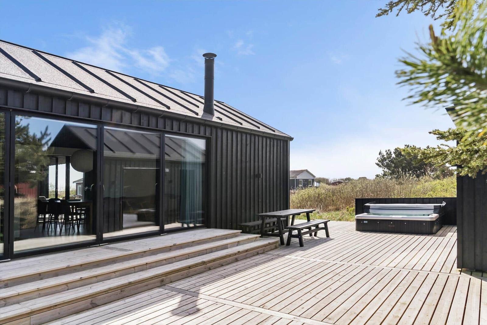 Moderne Holzhütte mit großem Terrassenbereich, Hot tub und Sitzgelegenheit.