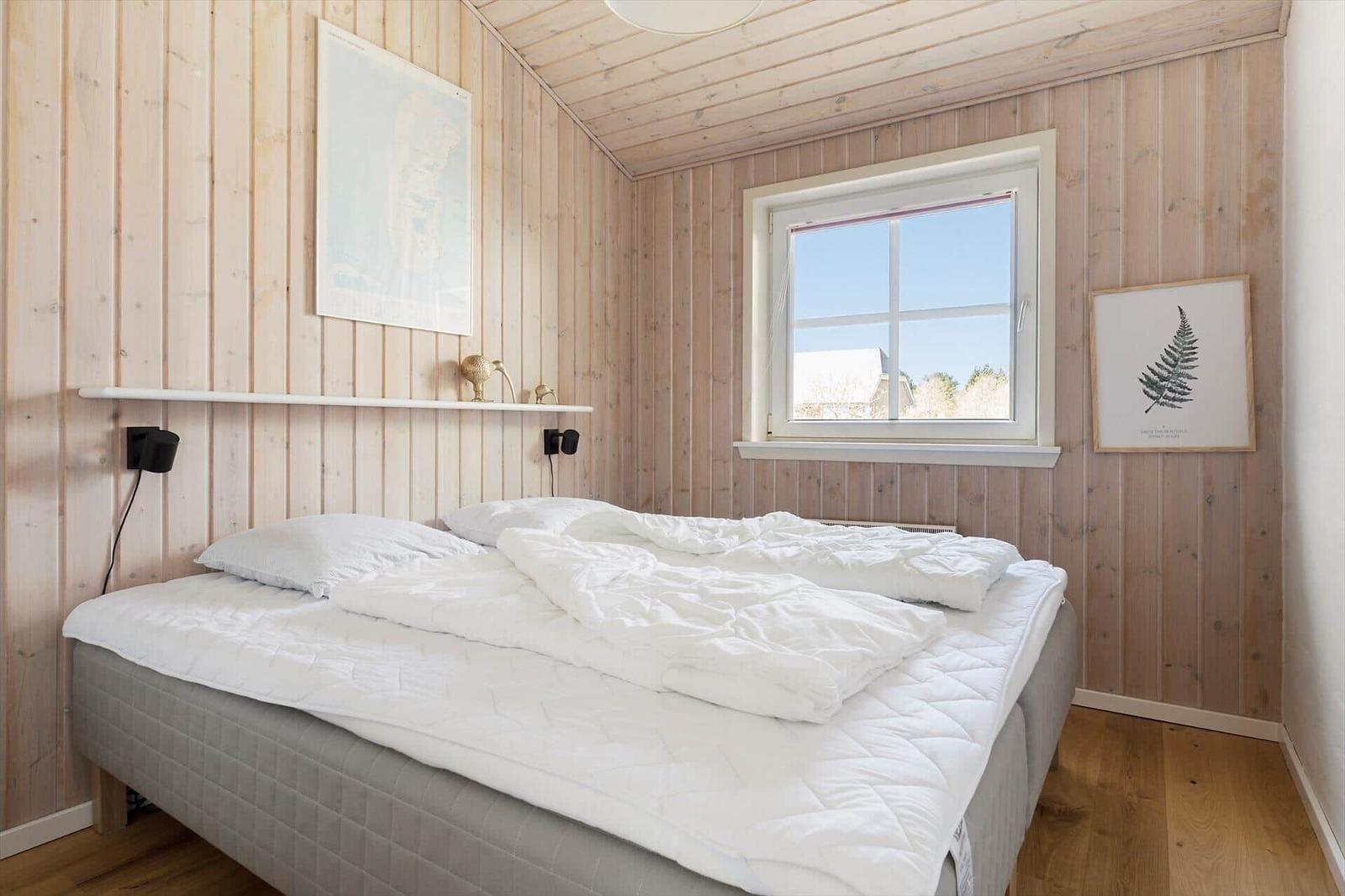 Schlafzimmer mit Holzwand, Bett und Fenster
