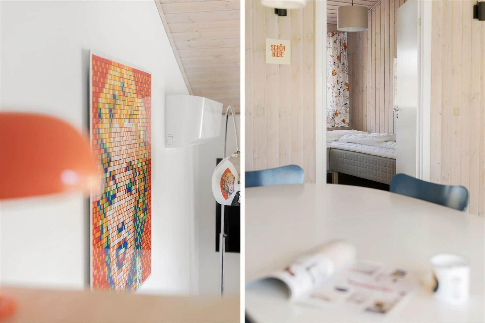 Kleines Schlafzimmer mit Bett und Holzwand. Wohnbereich mit Wandbild und Tisch.