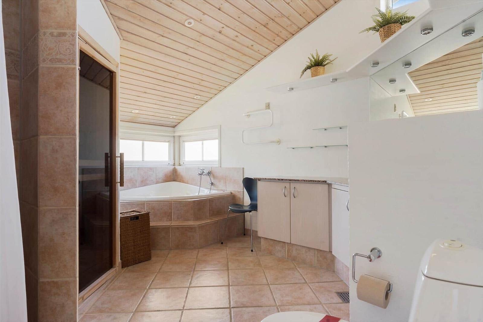 Badezimmer mit Badewanne, Holzdecke und Pflanzen