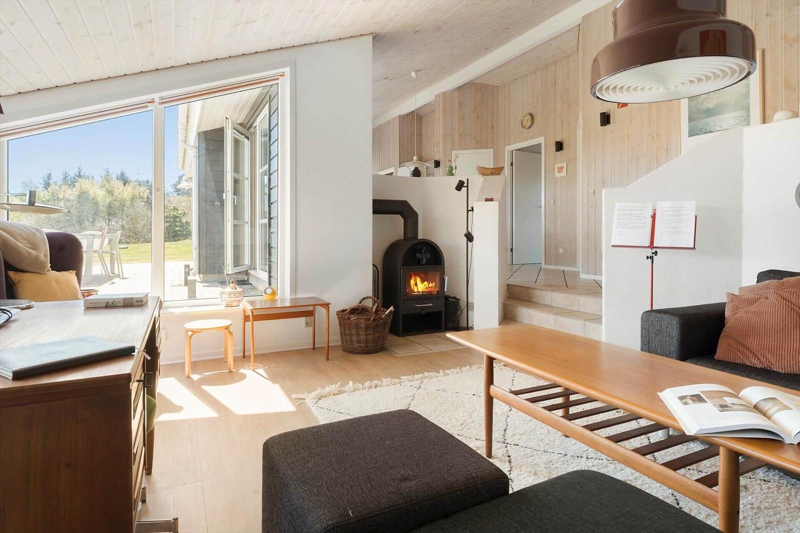 Wohnzimmer mit Kamin, Holzmöbel und Blick auf den Garten.