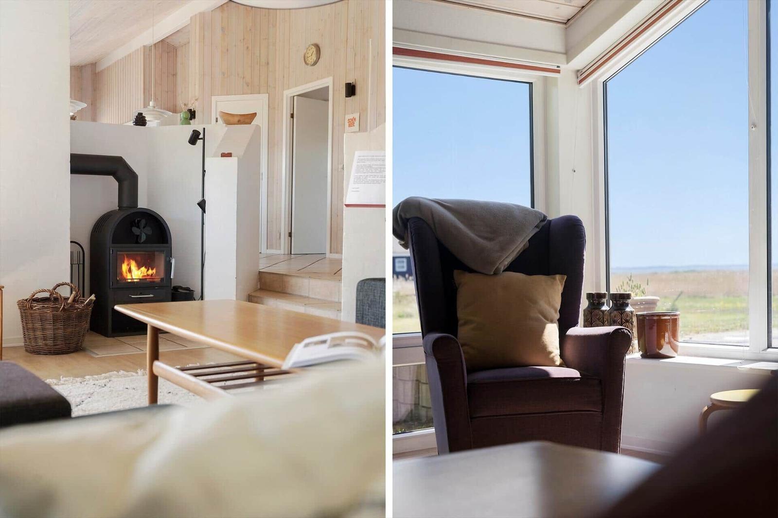 Wohnraum mit Kamin und Sitzgelegenheit vor großem Fenster mit Blick auf Landschaft